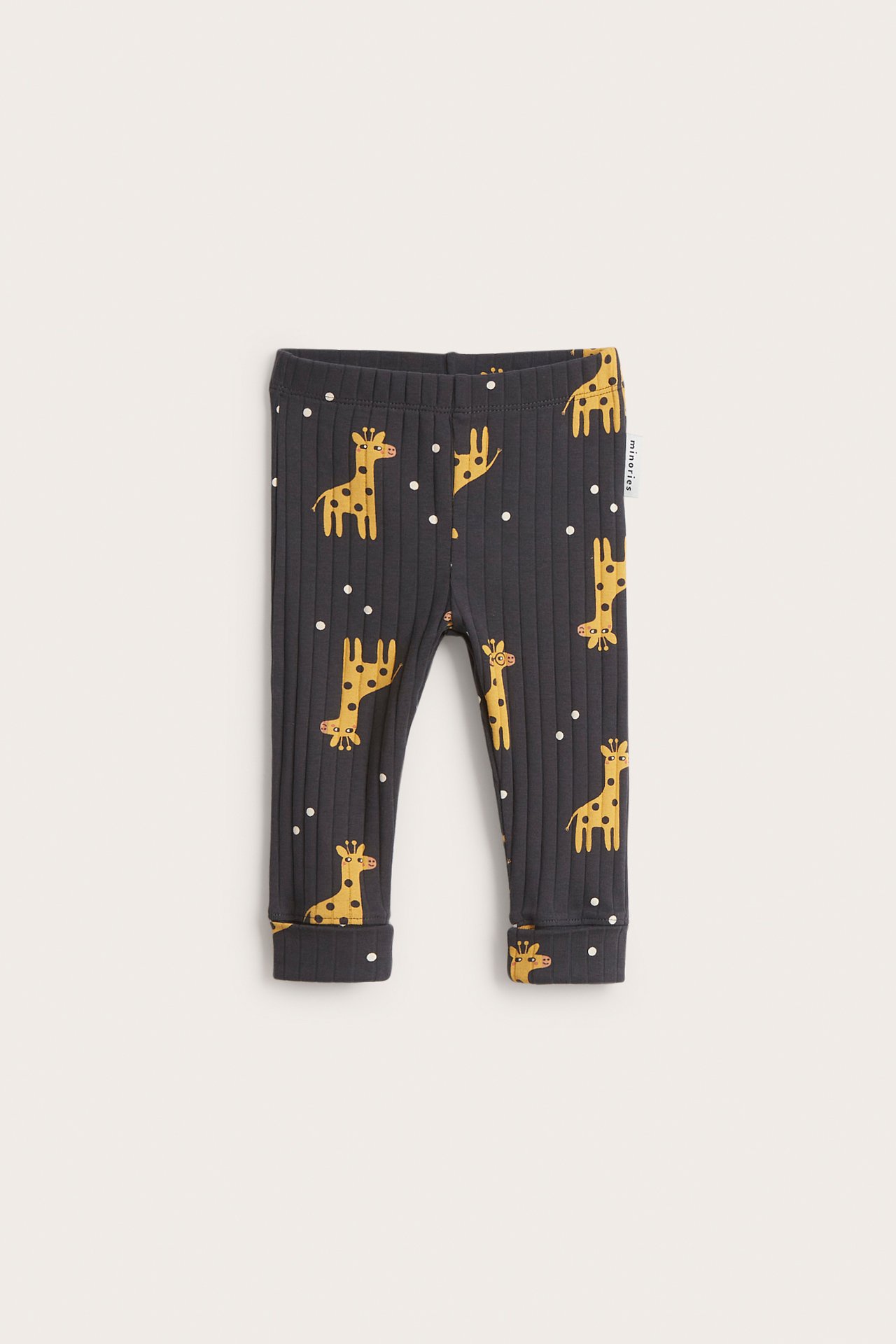 Framsida av svarta ribbade babyleggings med gult giraffmönster, resår i midjan och nedvikbara muddar.