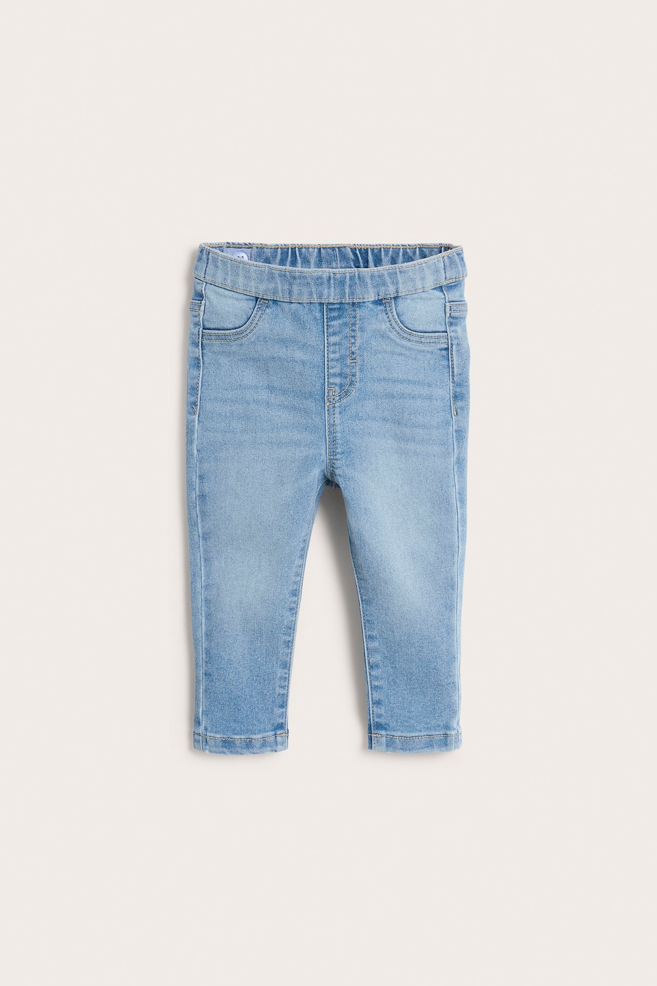 Framifrån: babyjeansleggings i ljus denim med resår i midjan och fusksfickor fram.