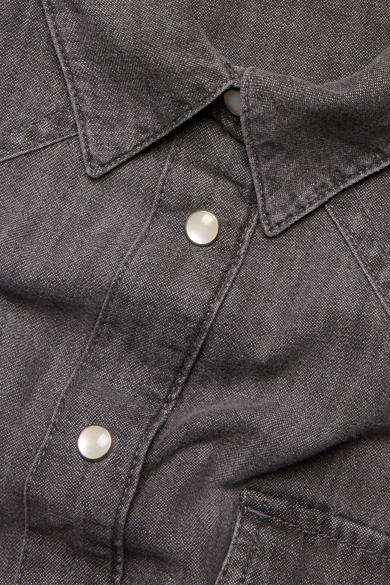 Zbliżenie szarej dżinsowej sukienki koszulowej z kołnierzem i jasnymi zatrzaskami.