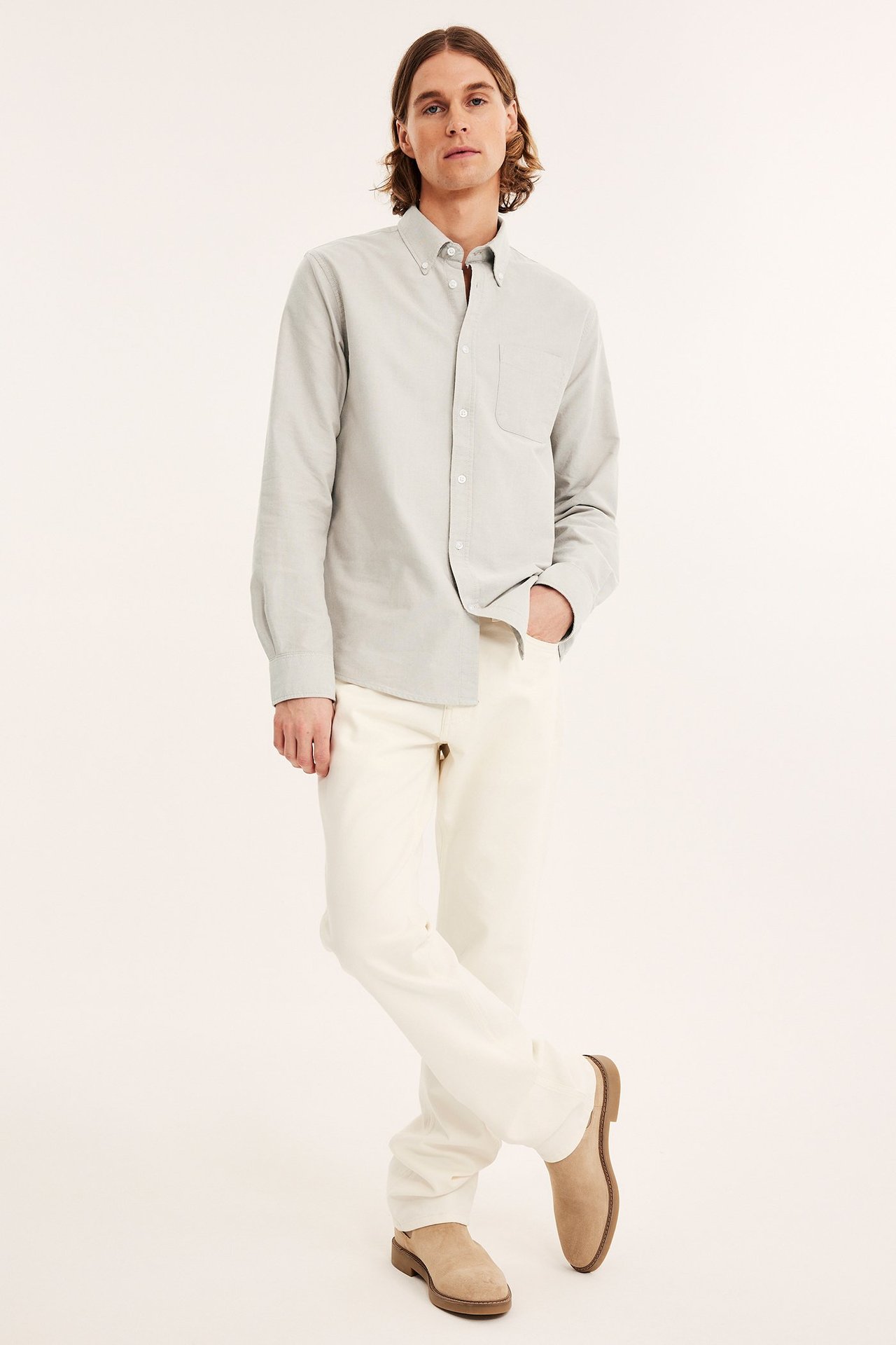 Edestä: mies vaaleanbeigessä meleeratussa regular fit oxford-paidassa, kermanvärisissä housuissa ja beigissä mokkakengissä.