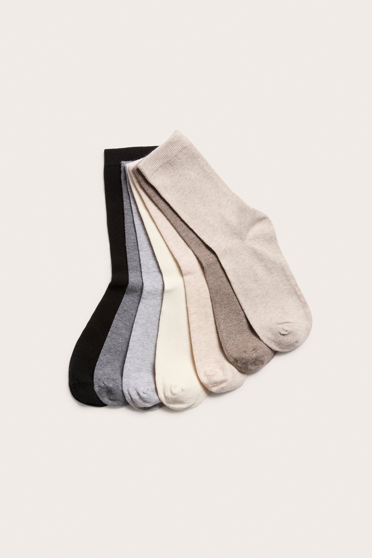 Ovenfra sett, syv bomullssokker i svart, grått, off-white og beige melert, vifteformet.