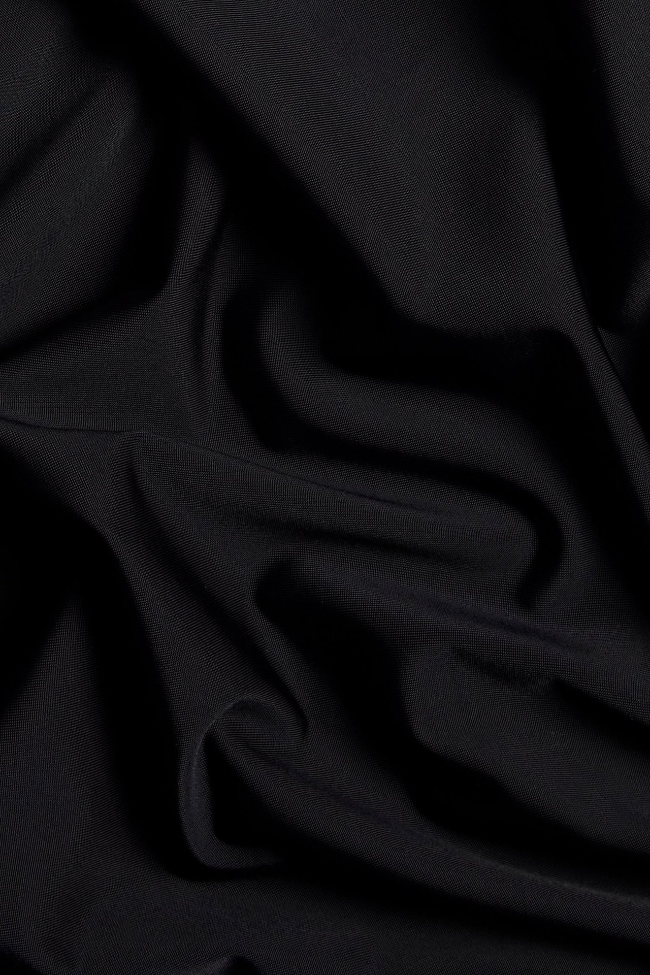 Zbliżenie czarnego, miękkiego, elastycznego materiału z fałdami.