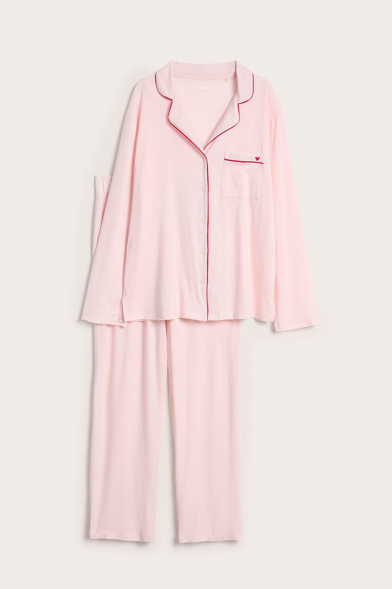 Edestä: vaaleanpunainen lyocell-pyjama punaisella tereellä, sydänkirjonta paidan taskussa.