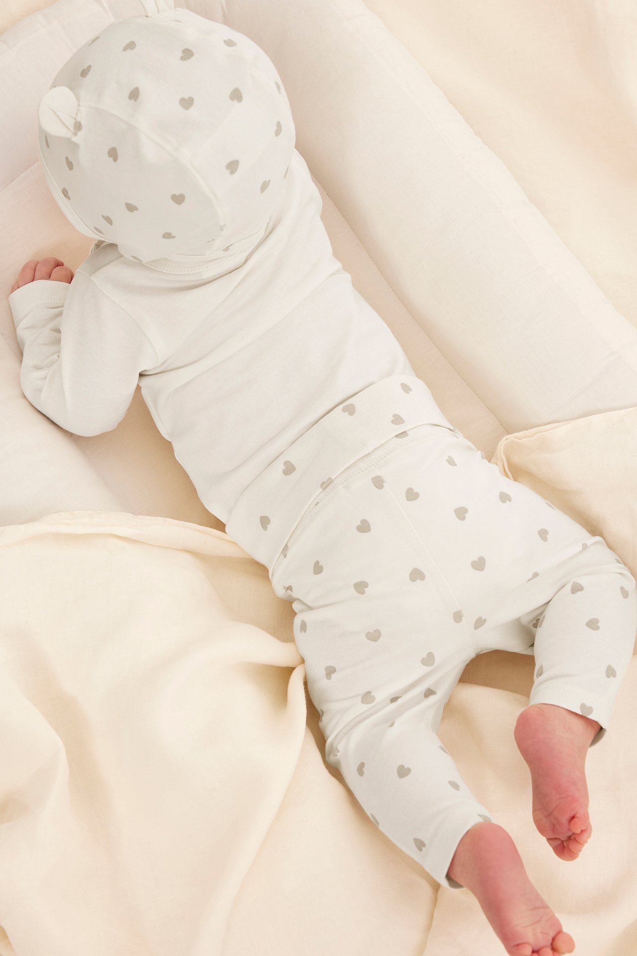 Uppifrån: baby i off-white mönstrat bomullsset med tröja, leggings och mössa med öron.