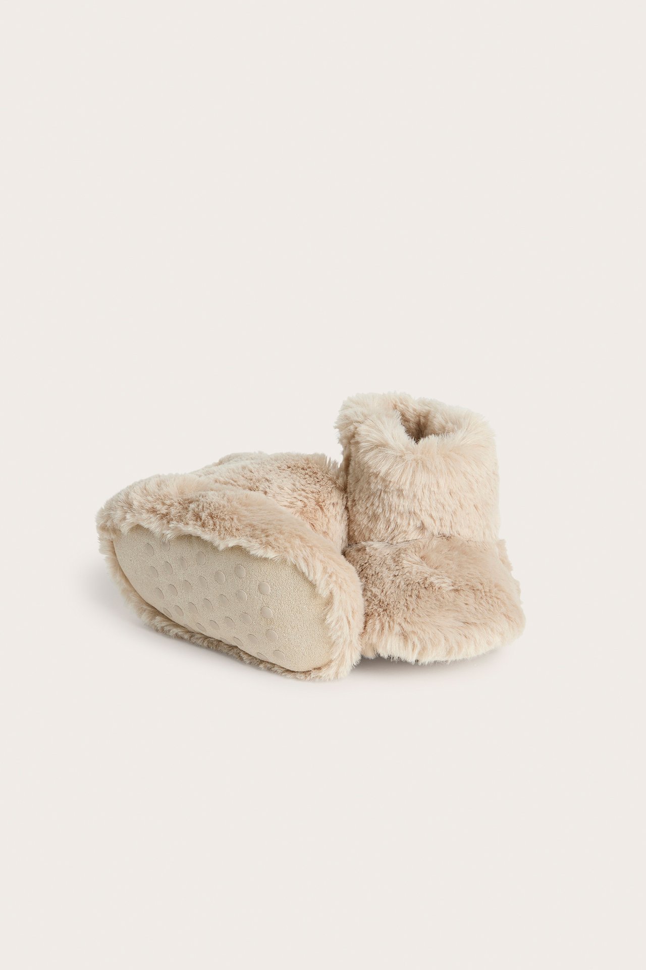 Närbild av beiga pile-babytossor med dold kardborreknäppning och halkfria sulor.