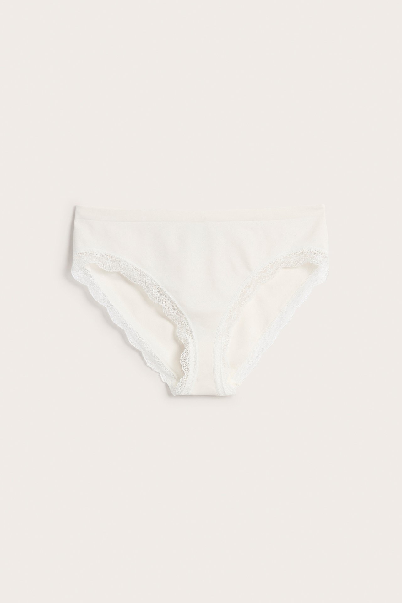 Frontvisning av offwhite sømløse brief-truser med en delikat blondekant.