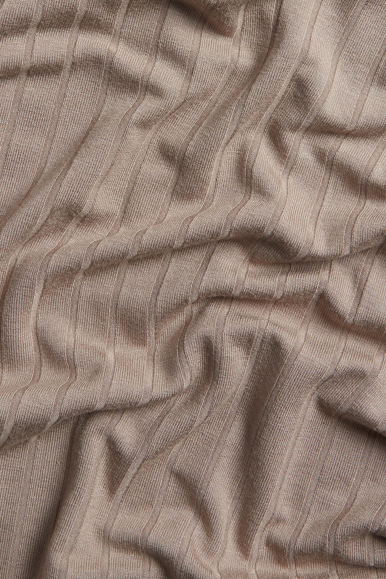 Nærbilde av mørk beige lang ribbet T-skjortestoff med synlige folder.