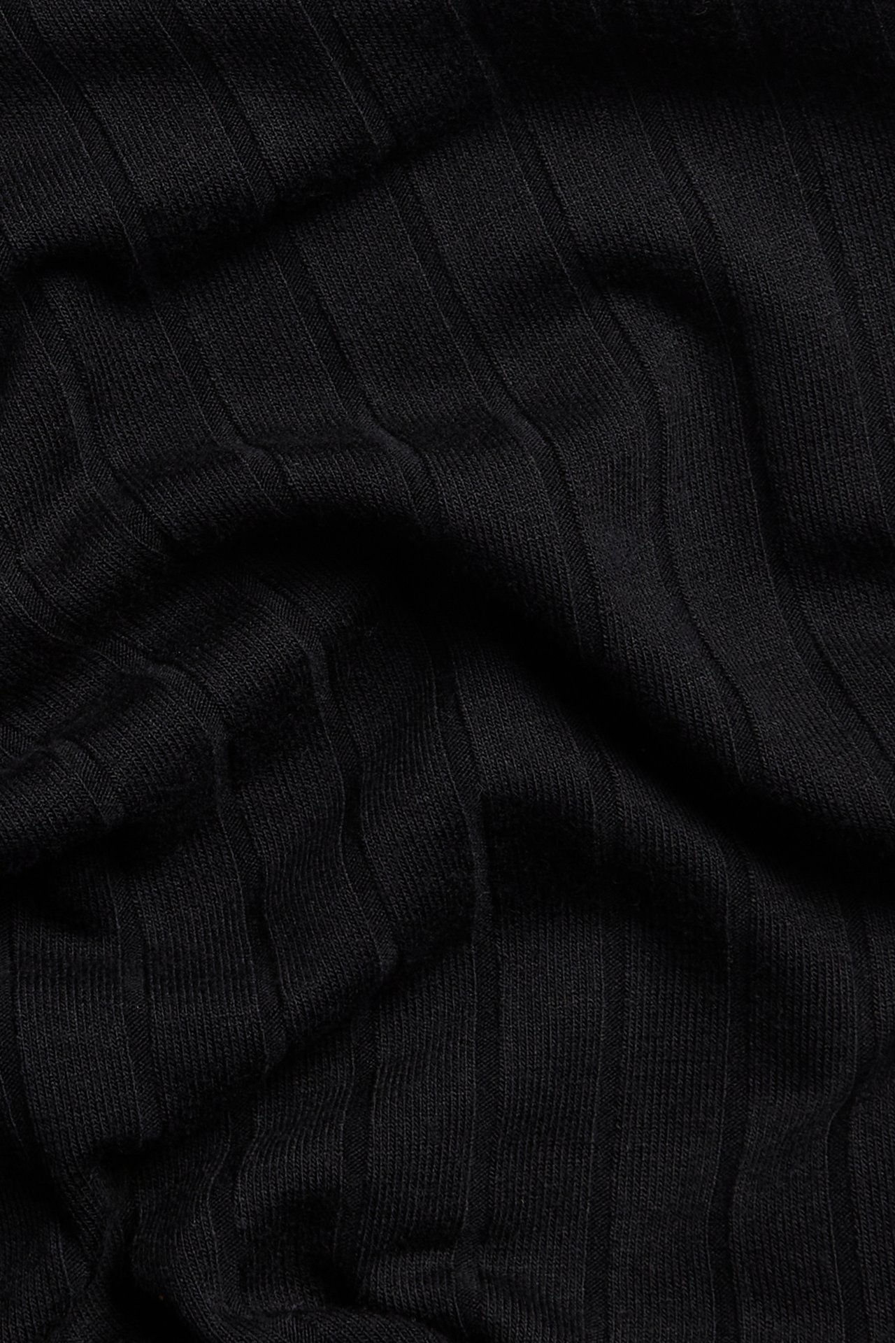 Närbild av svart ribbat jerseymaterial från pull on-byxor.