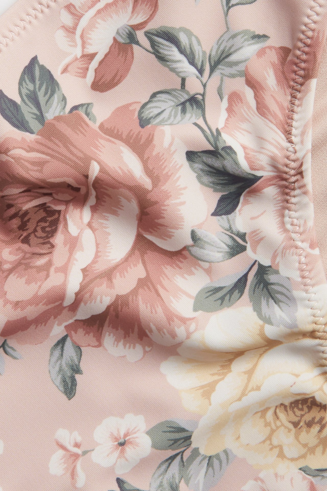 Närbild av en rosa blommig bikinitrosa med mönster av rosa och gula rosor.