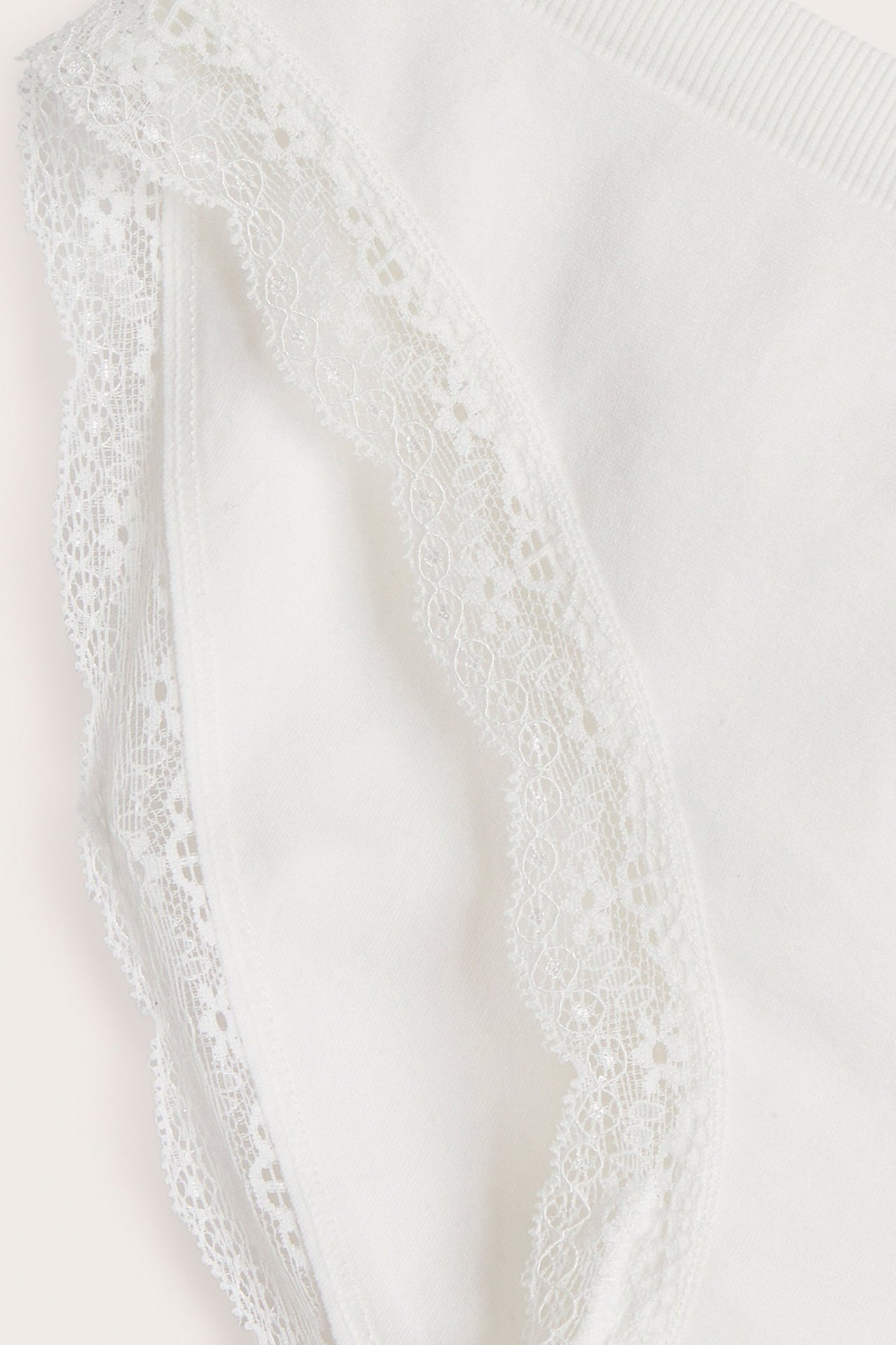 Zbliżenie na kremowe bezszwowe figi z delikatnym koronkowym wykończeniem wzdłuż krawędzi.