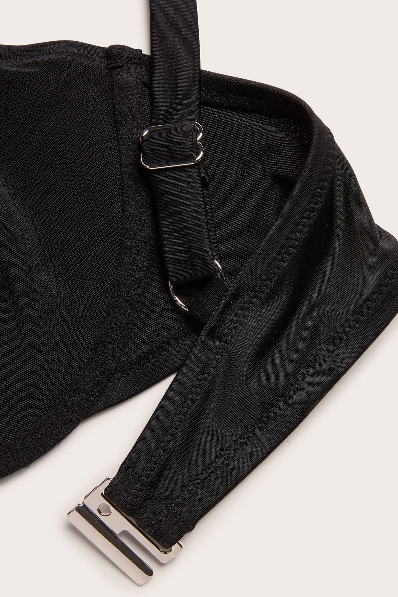 Zbliżenie czarnego biustonosza bikini z regulowanym ramiączkiem i srebrnym zapięciem z tyłu.