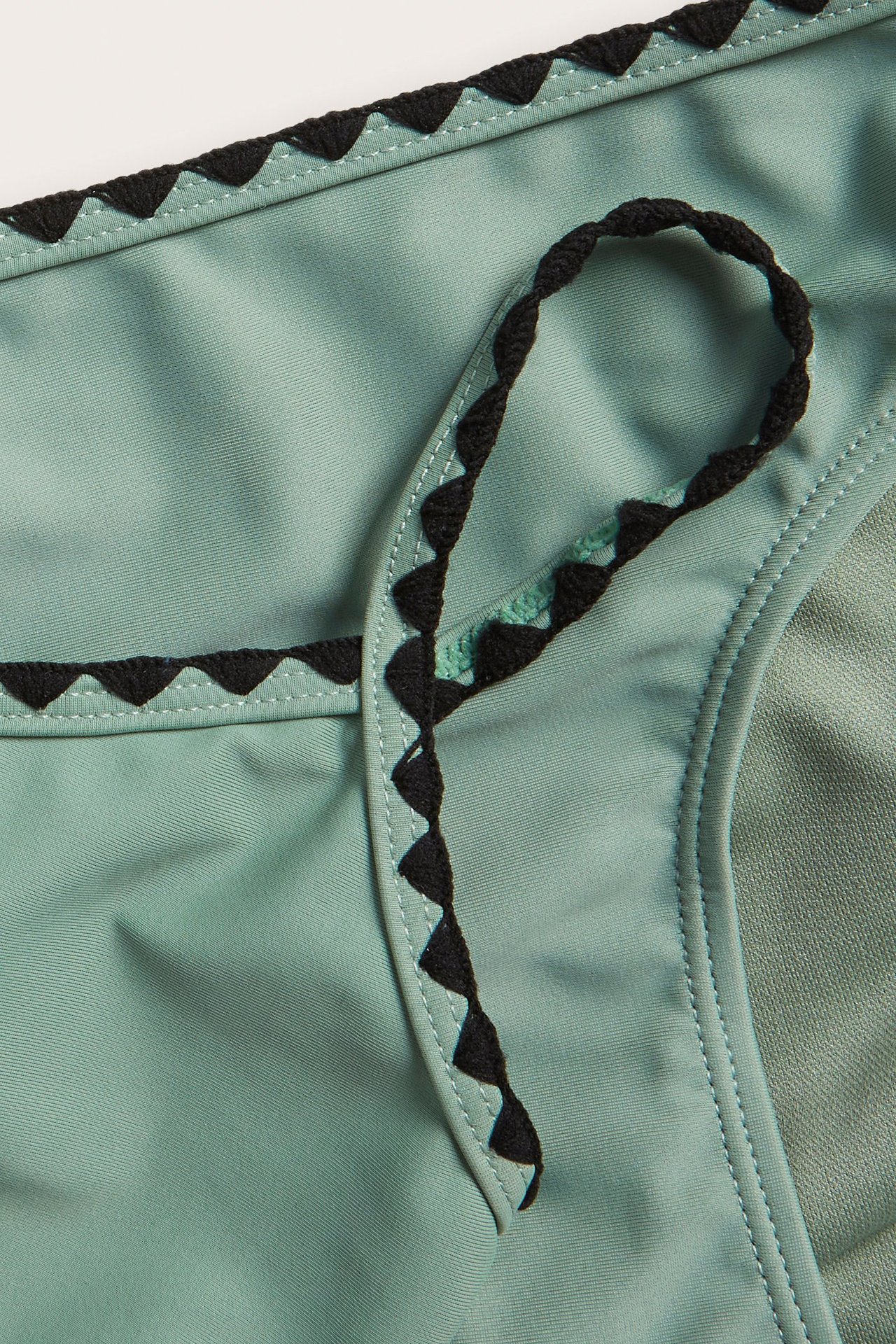 Lähikuva vihreistä bikinialaosista, joissa on musta jacquard-neulottu reuna ja yhteensopiva kiristysnyöri.