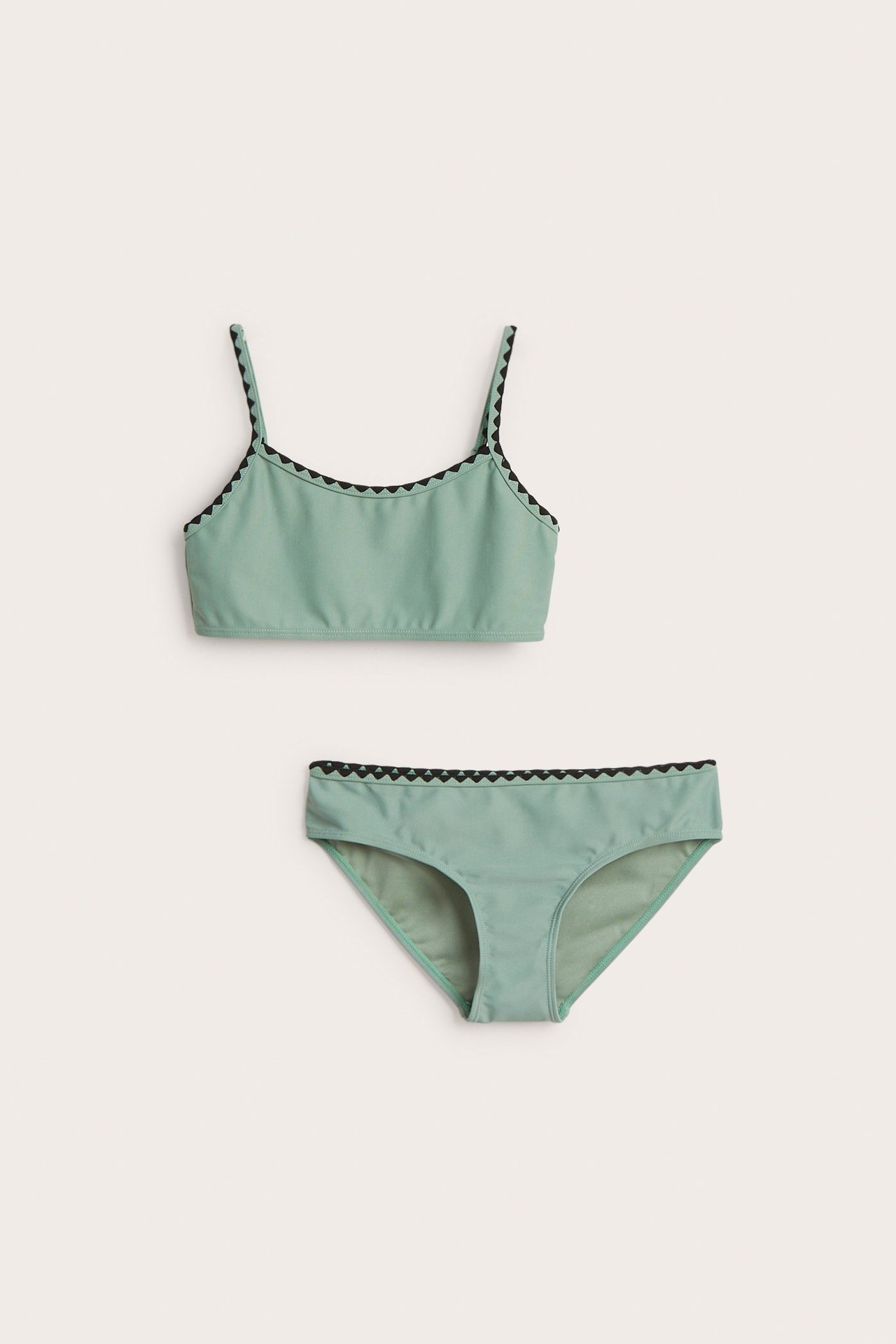 Edestäpäin, vihreät lasten bikinit, joissa musta aaltokuvioinen reuna ylä- ja alaosassa.