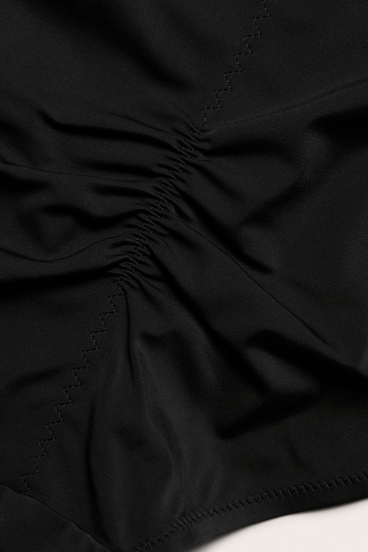 Zbliżenie czarnych modelujących fig typu hipster z marszczonym detalem i zygzakowatymi szwami.