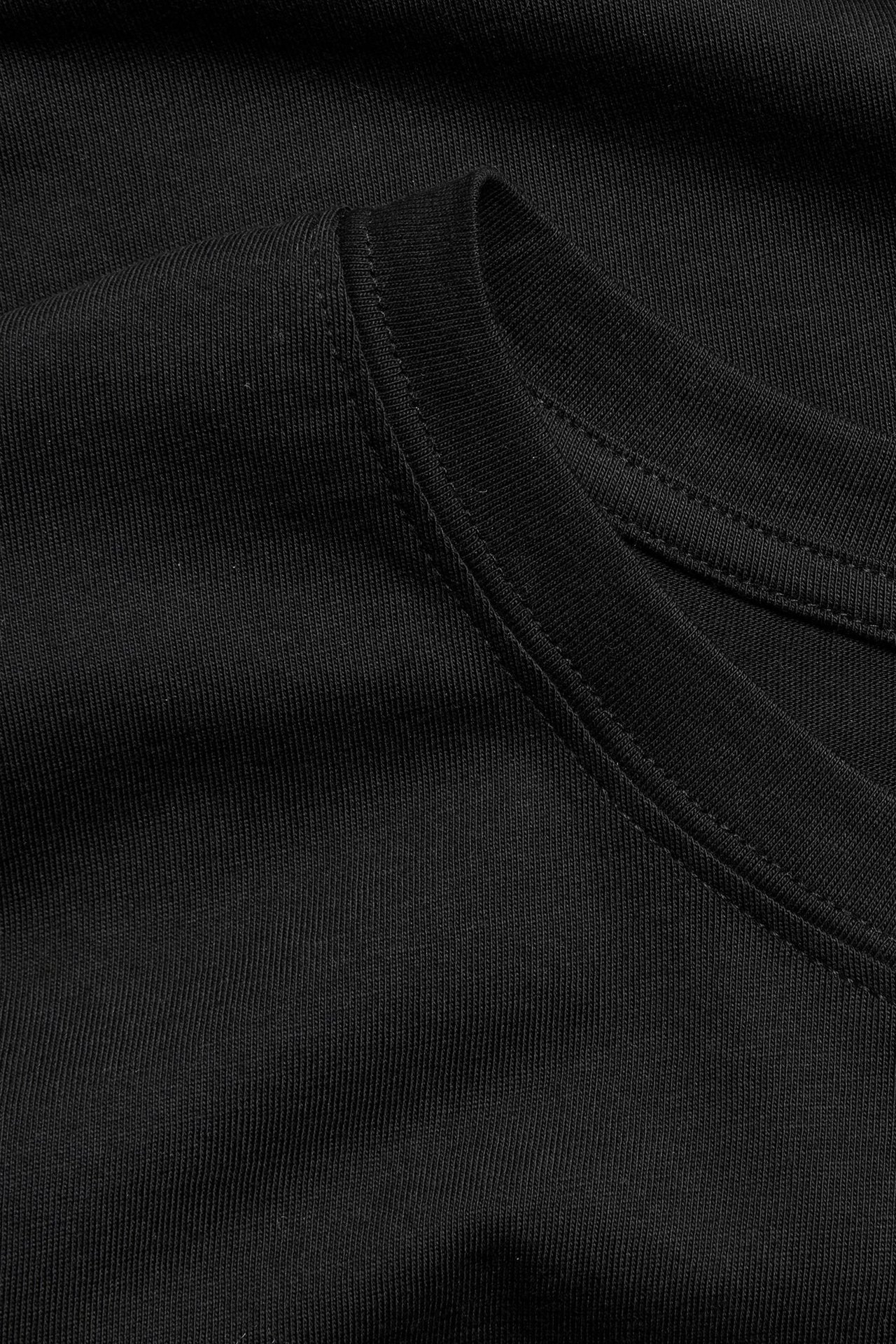 Zbliżenie na czarny, jednolity bawełniany T-shirt z prążkowaną fakturą i okrągłym dekoltem.