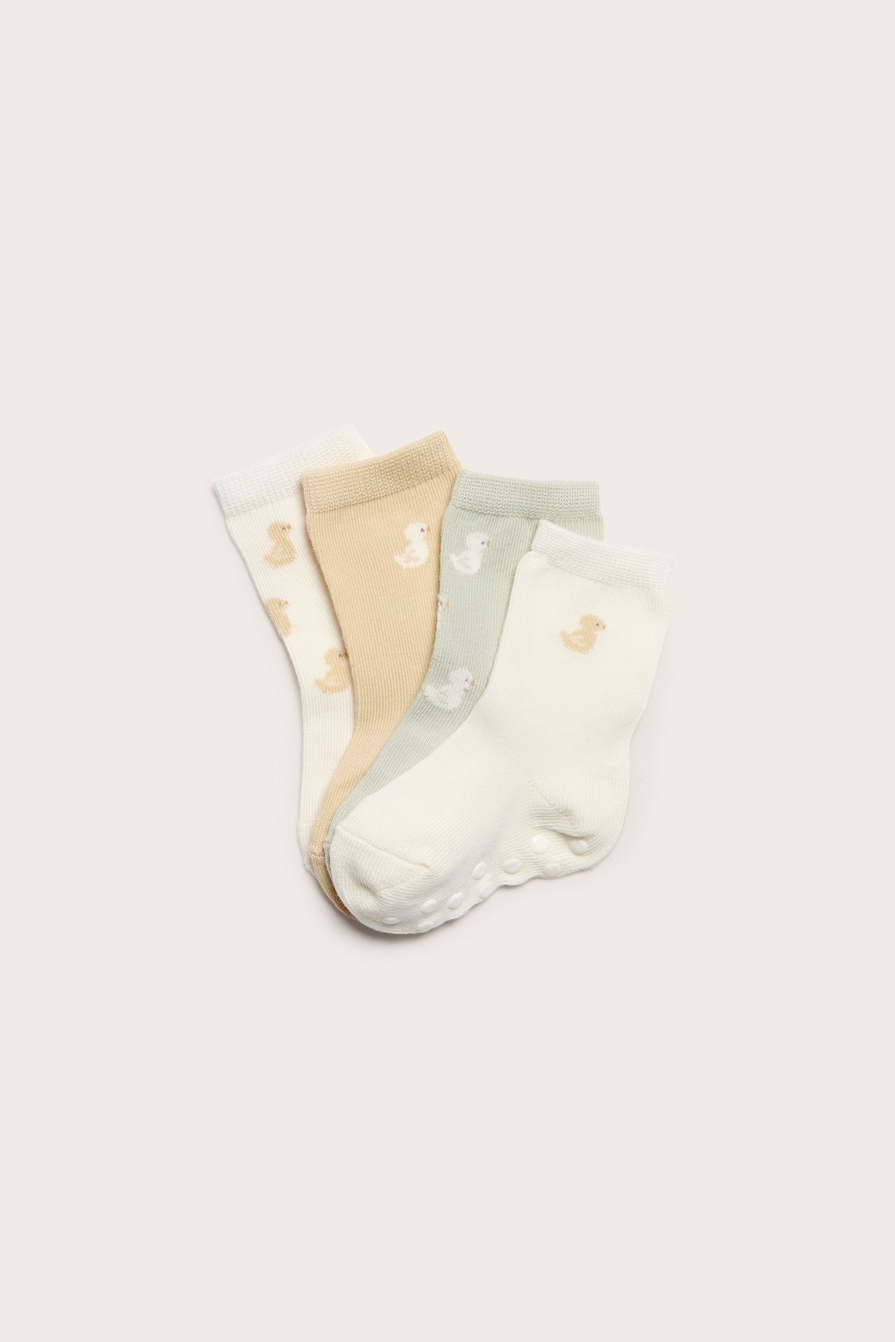 Övervy av fyra pastellfärgade babysockor: gräddvita, beige, ljusgröna, med ank-mönster och anti-slip sulor.