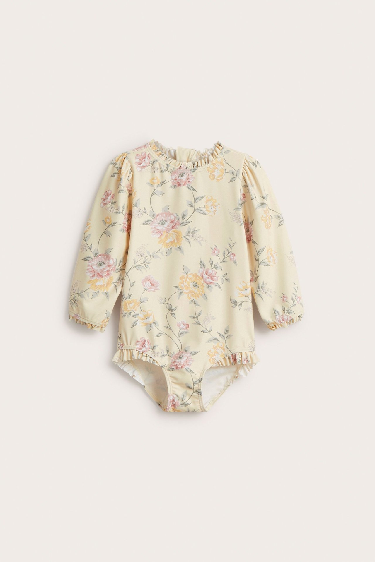 Edestä: vaaleankeltainen kukkakuvioinen pitkähihainen lasten UV-uimapuku, jossa röyhelöitä ja vetoketju takana.