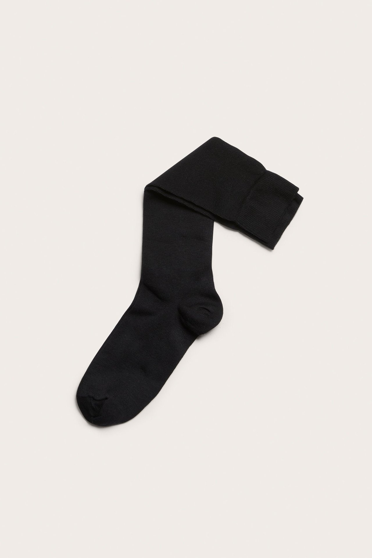 Widok z góry na jedną czarną, jednolitą podkolanówkę z mieszanki bawełny.
