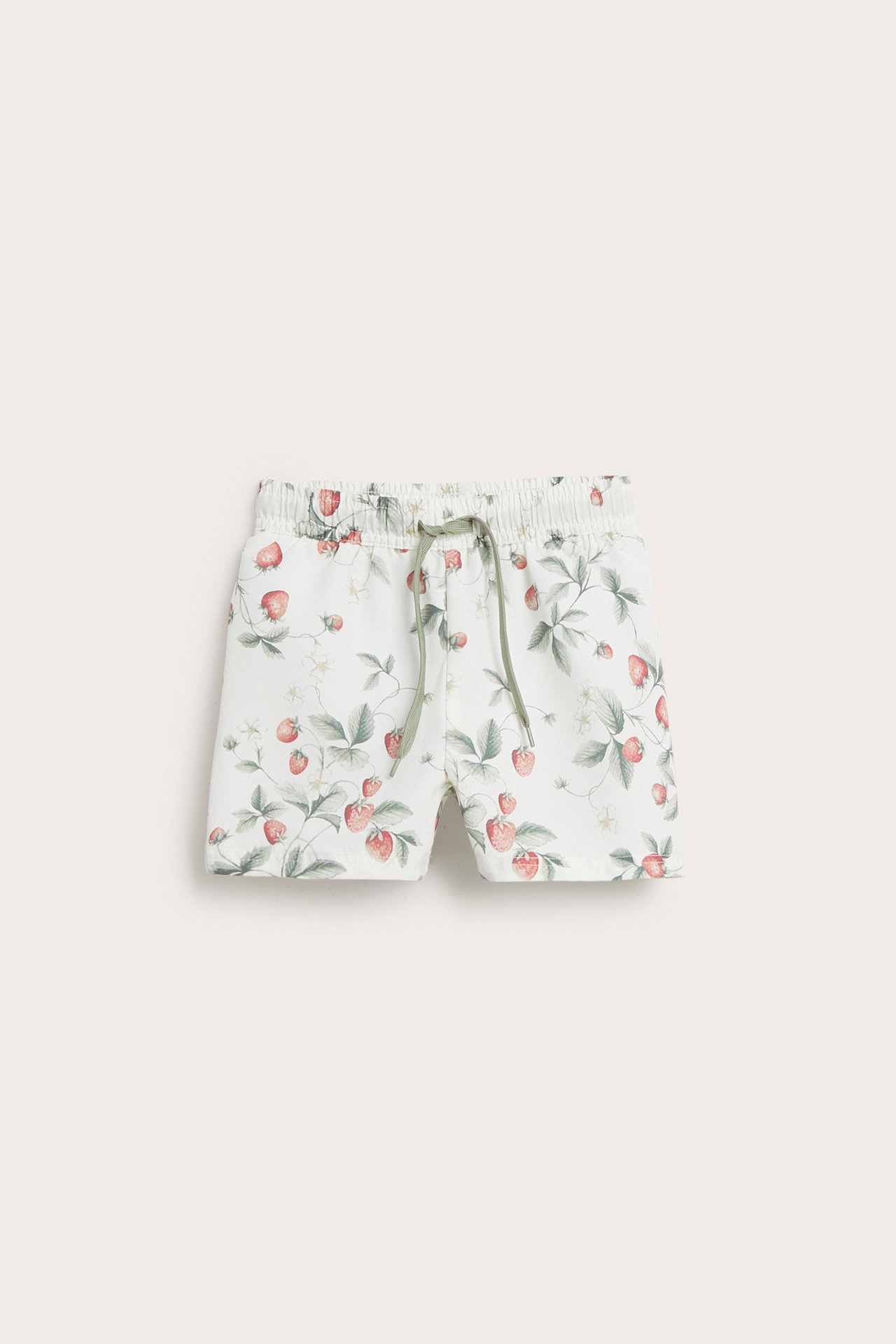 Frontvy av offwhite baby/barn badshorts med jordgubbsmönster och grön dragsko.