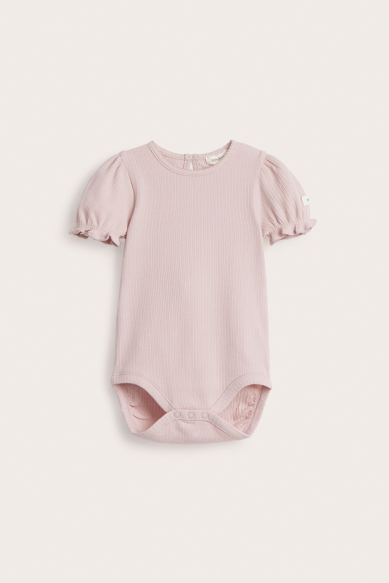 Framifrån: babybody i rosa ribbad jersey med korta puffärmar, picotsöm och tryckknappar.