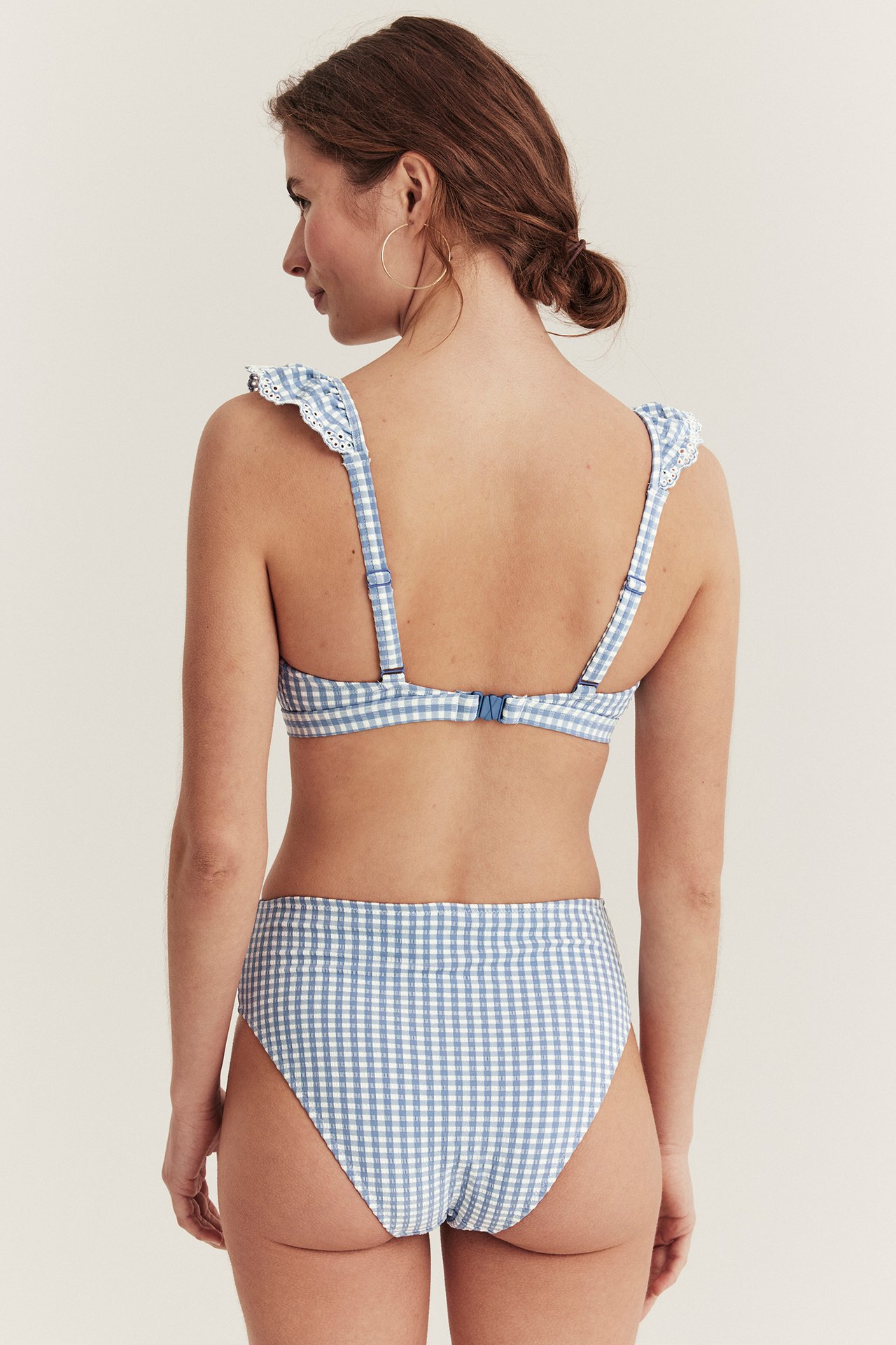 Kvinne, bakfra, i blå- og hvitrutete høy midje bikinitruse og matchende bikinitopp.