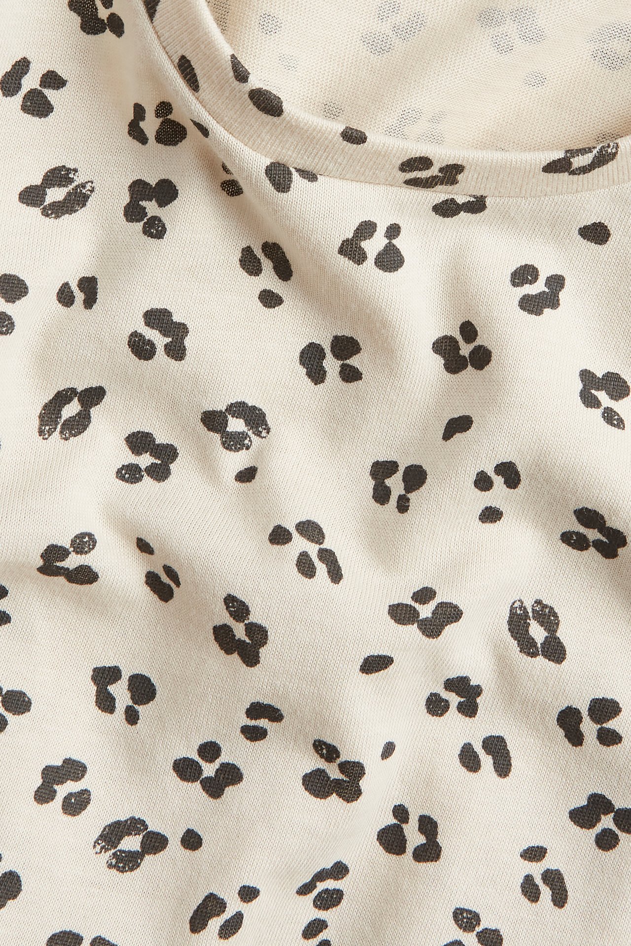 Närbild av beige bomullstyg med mörkgrått leopardmönster.