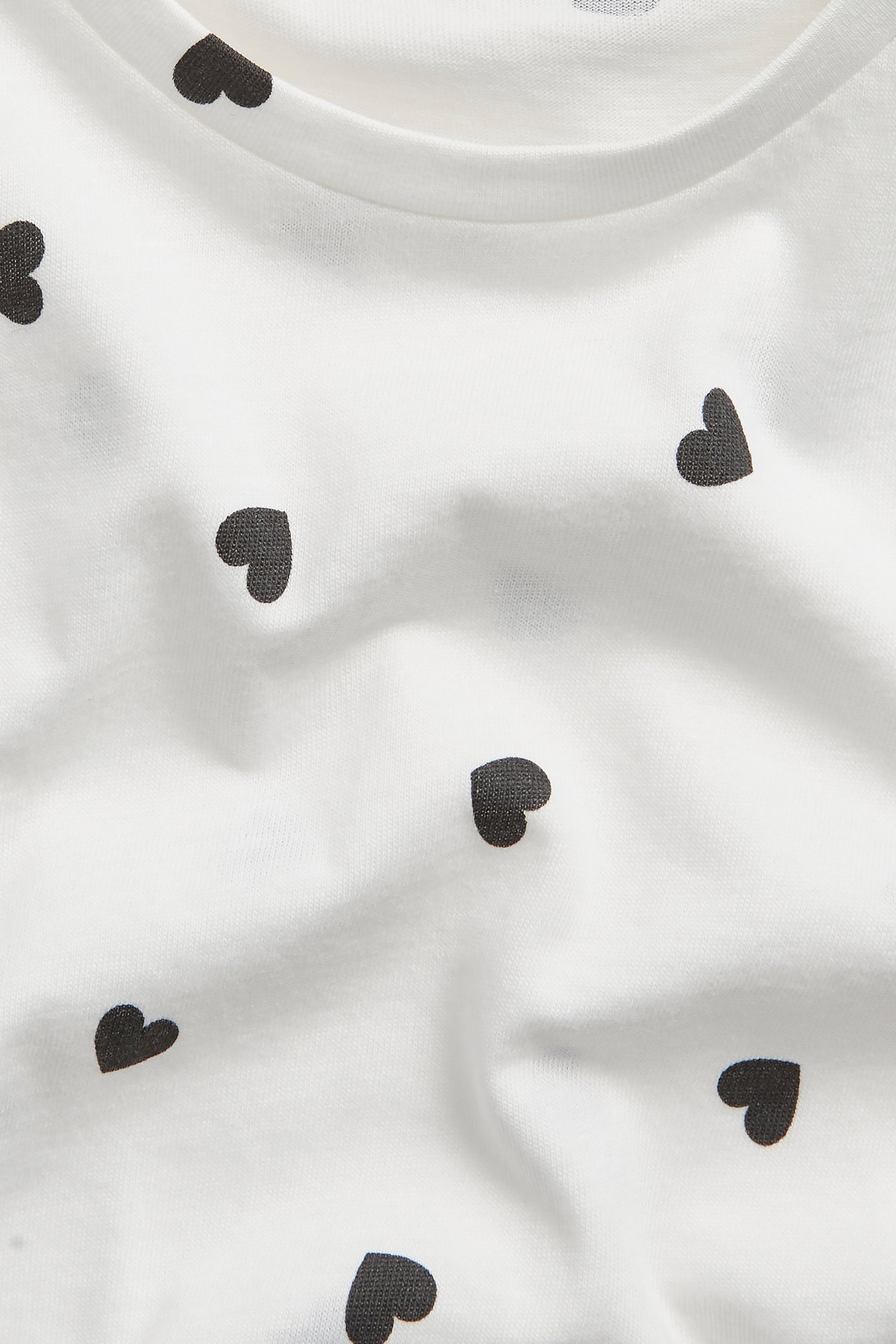 Zbliżenie na biały bawełniany t-shirt z czarnym wzorem serc.