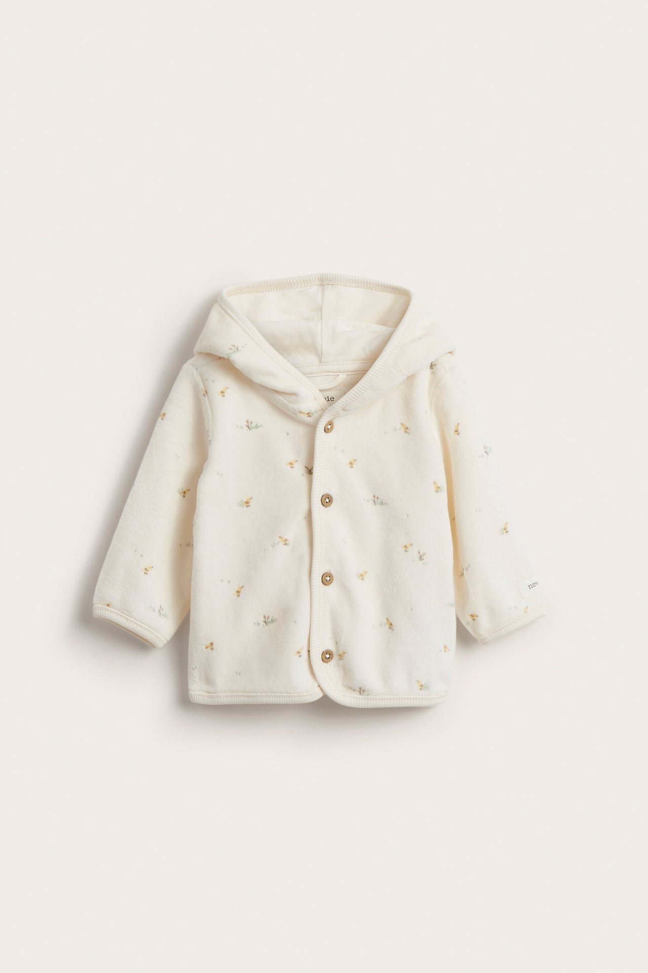 Forfra: Offwhite velour babyhettegenser med blomstermønster og treknapper.