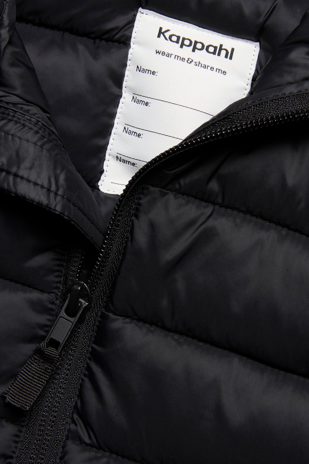 Zbliżenie czarnej pikowanej lekkiej kamizelki z czarnym zamkiem błyskawicznym i białą metką wewnętrzną.