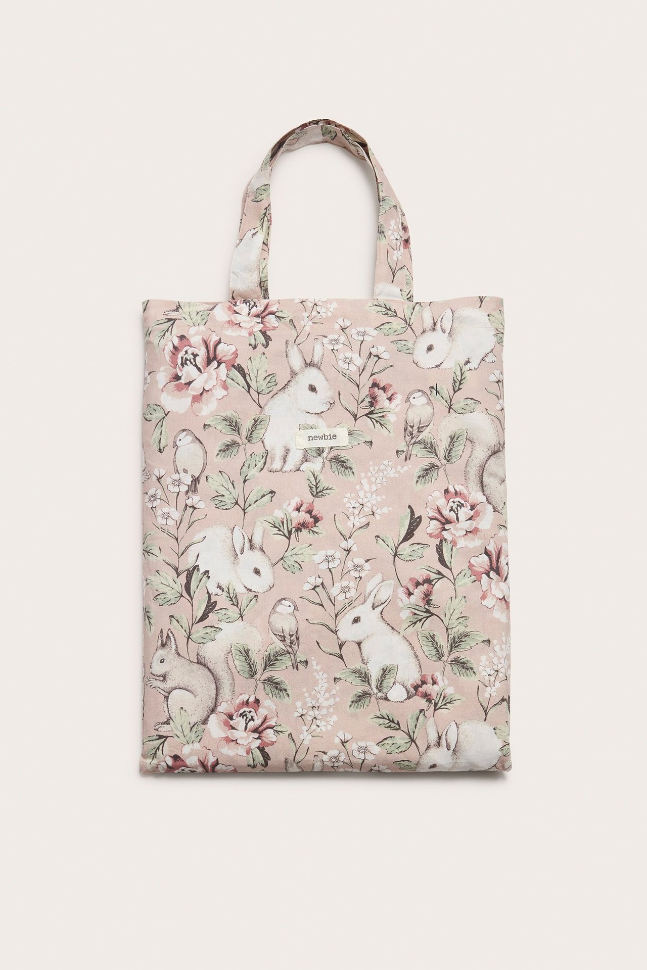 Frontvy av en rosa tygpåse i bomull för bäddset, med handtag och blommigt djurmönster.