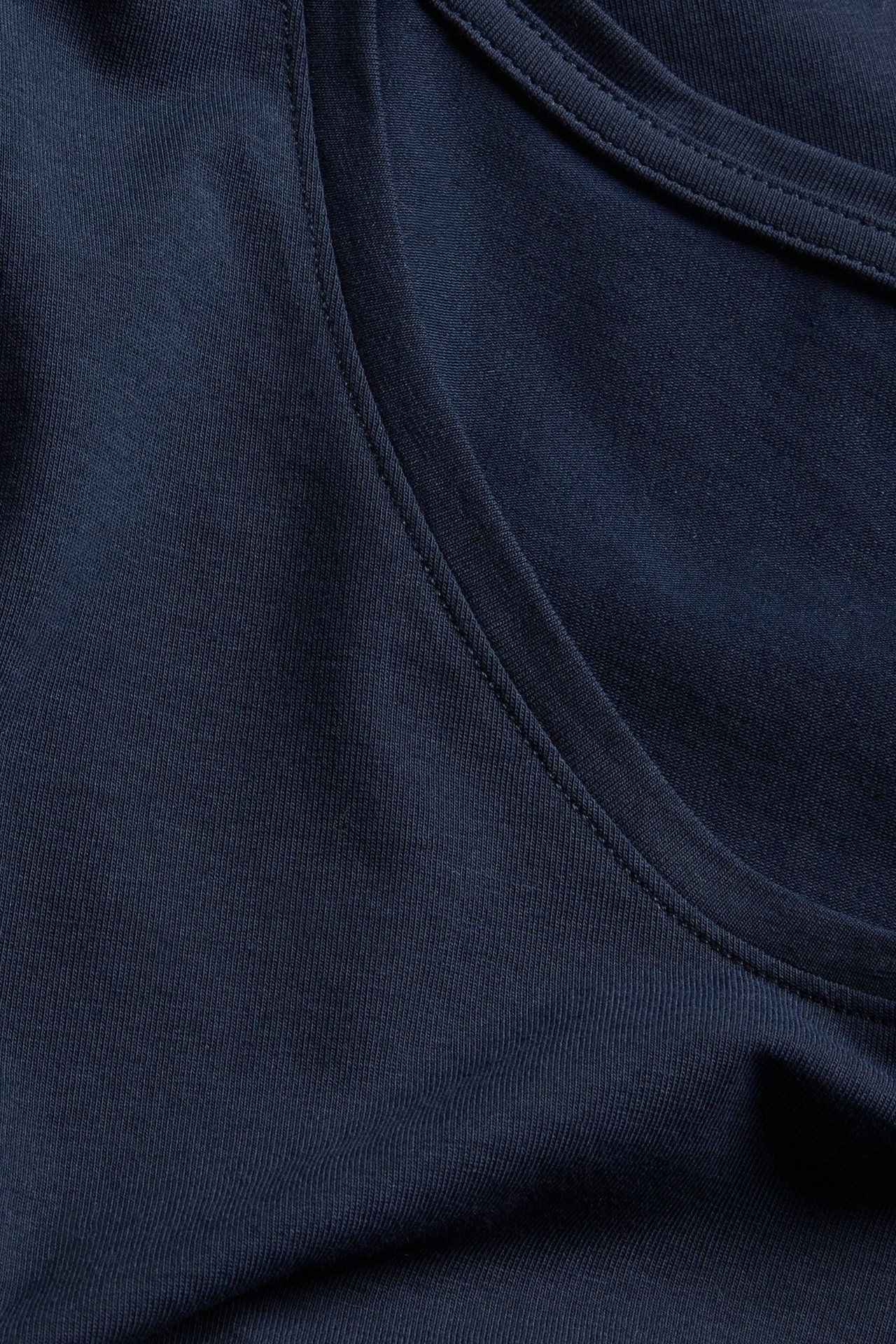 Nærbilde av en mørkeblå langermet topp med scoop-hals, i bomullsblanding.