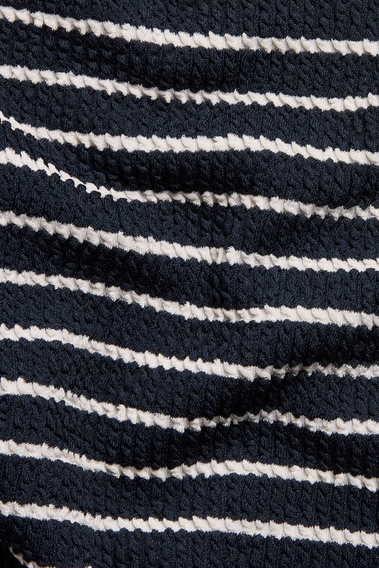 Zbliżenie na granatowy i biały, prążkowany, teksturowany materiał szortów kąpielowych.