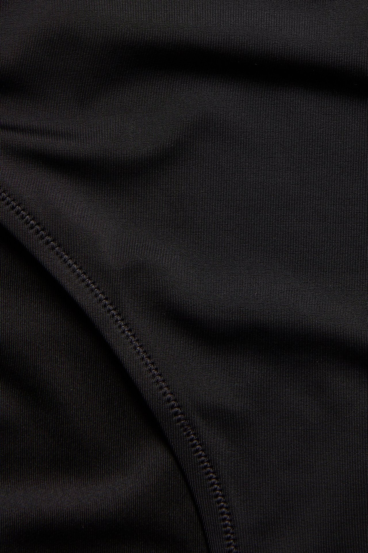 Zbliżenie na czarny, jednolity materiał od stroju kąpielowego z widocznymi szwami.