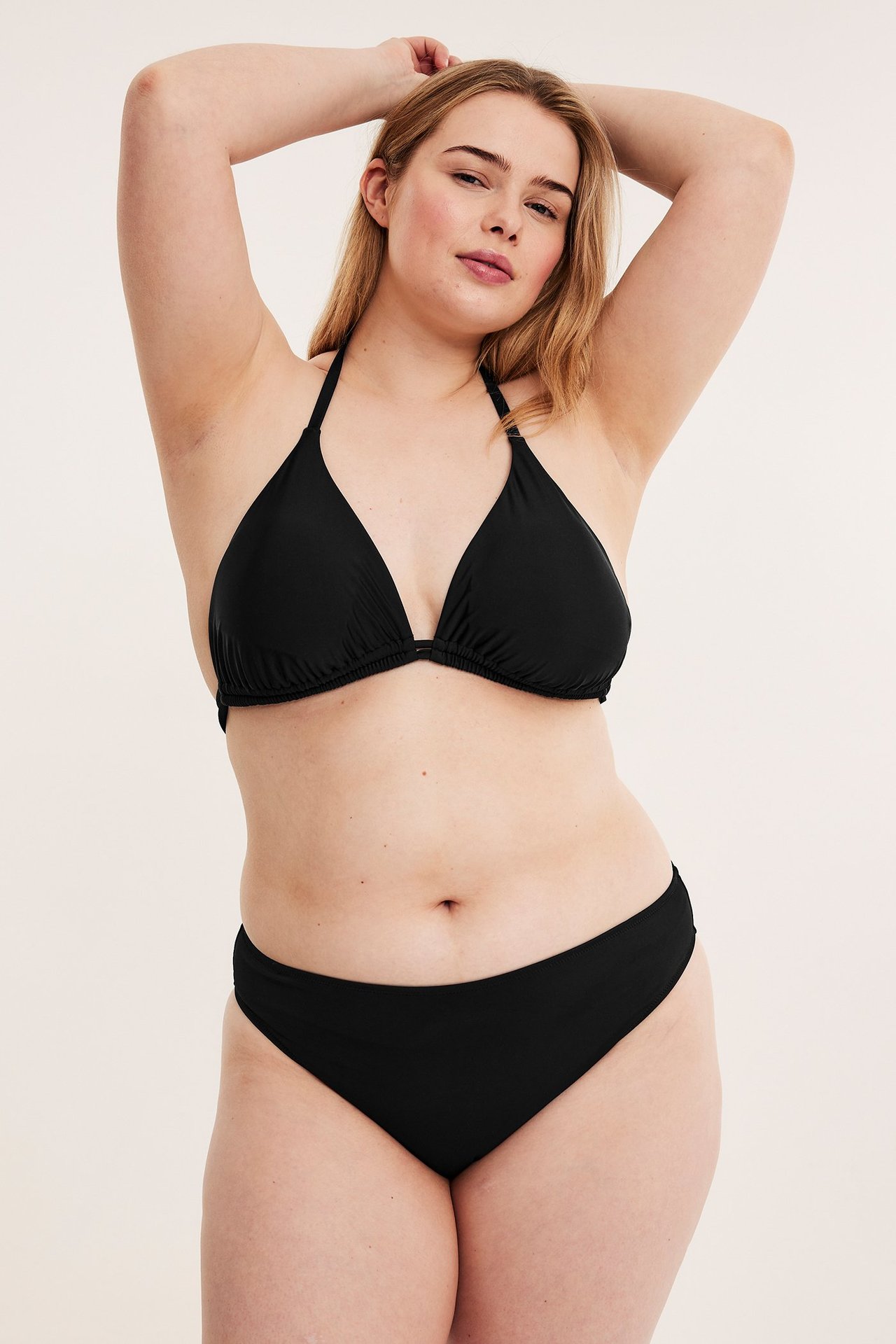 Widok z przodu kobiety w czarnych figach bikini z wysokim stanem i czarnym biustonoszu bikini.