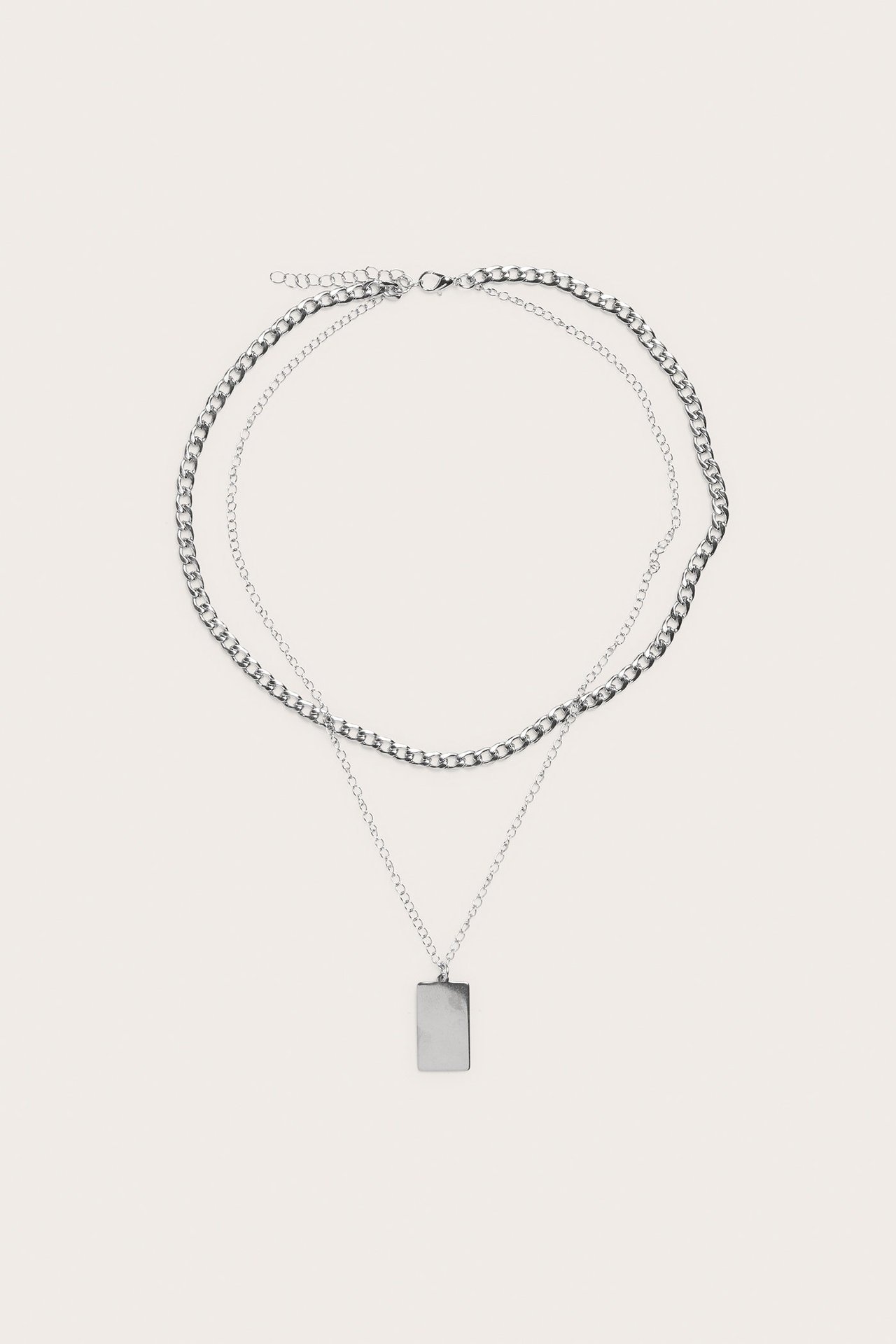 Widok z przodu srebrnego naszyjnika warstwowego z grubym łańcuchem pancerka i cienkim łańcuszkiem z prostokątną zawieszką.