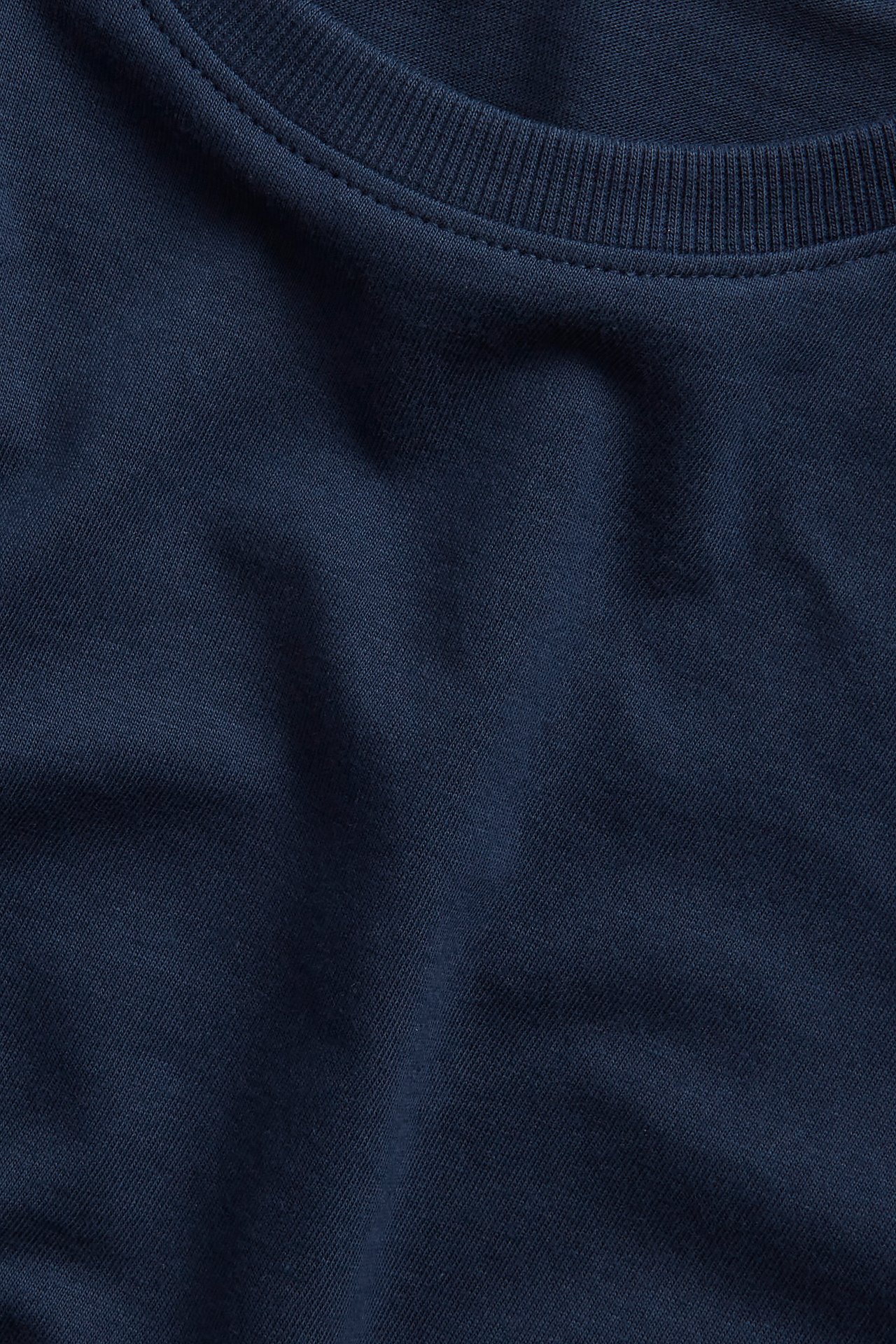 Närbild av en enfärgad marinblå t-shirt i bomull med ribbad rundhals.
