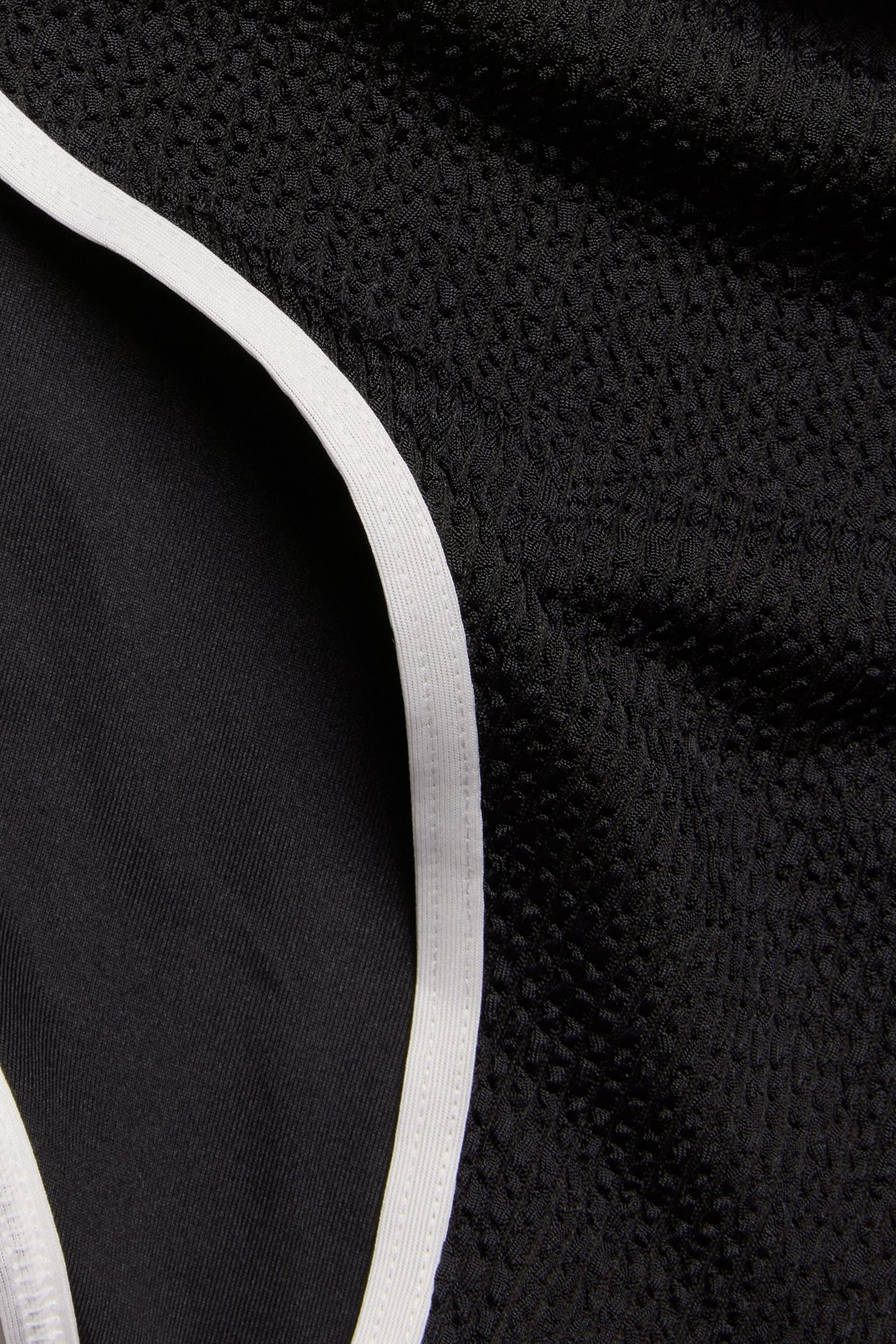 Zbliżenie czarnych, teksturowanych majtek bikini z białą elastyczną lamówką.