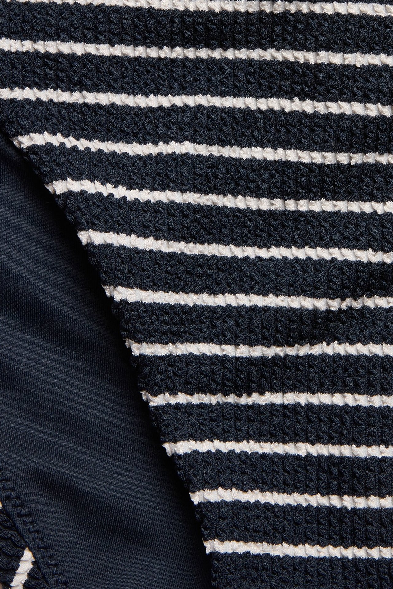 Zbliżenie na granatowe i białe paski fig bikini z teksturowanego materiału.