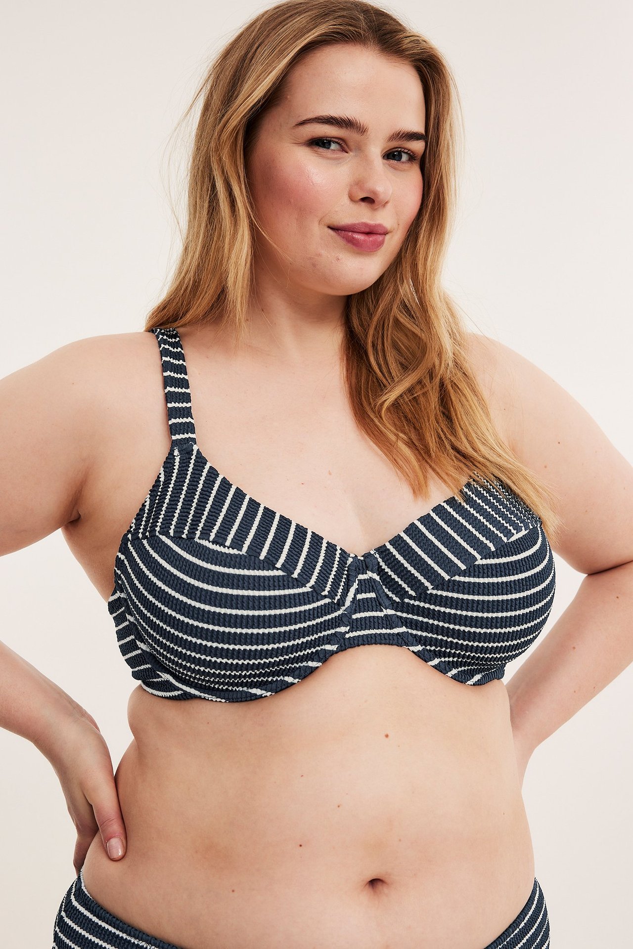 Widok z przodu: kobieta w granatowym, pasiastym biustonoszu bikini i pasujących majtkach.