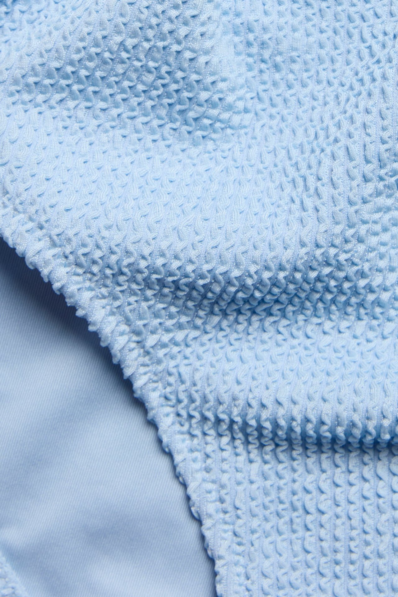 Zbliżenie na jasnoniebieskie, teksturowane figi kąpielowe z wysokim stanem.