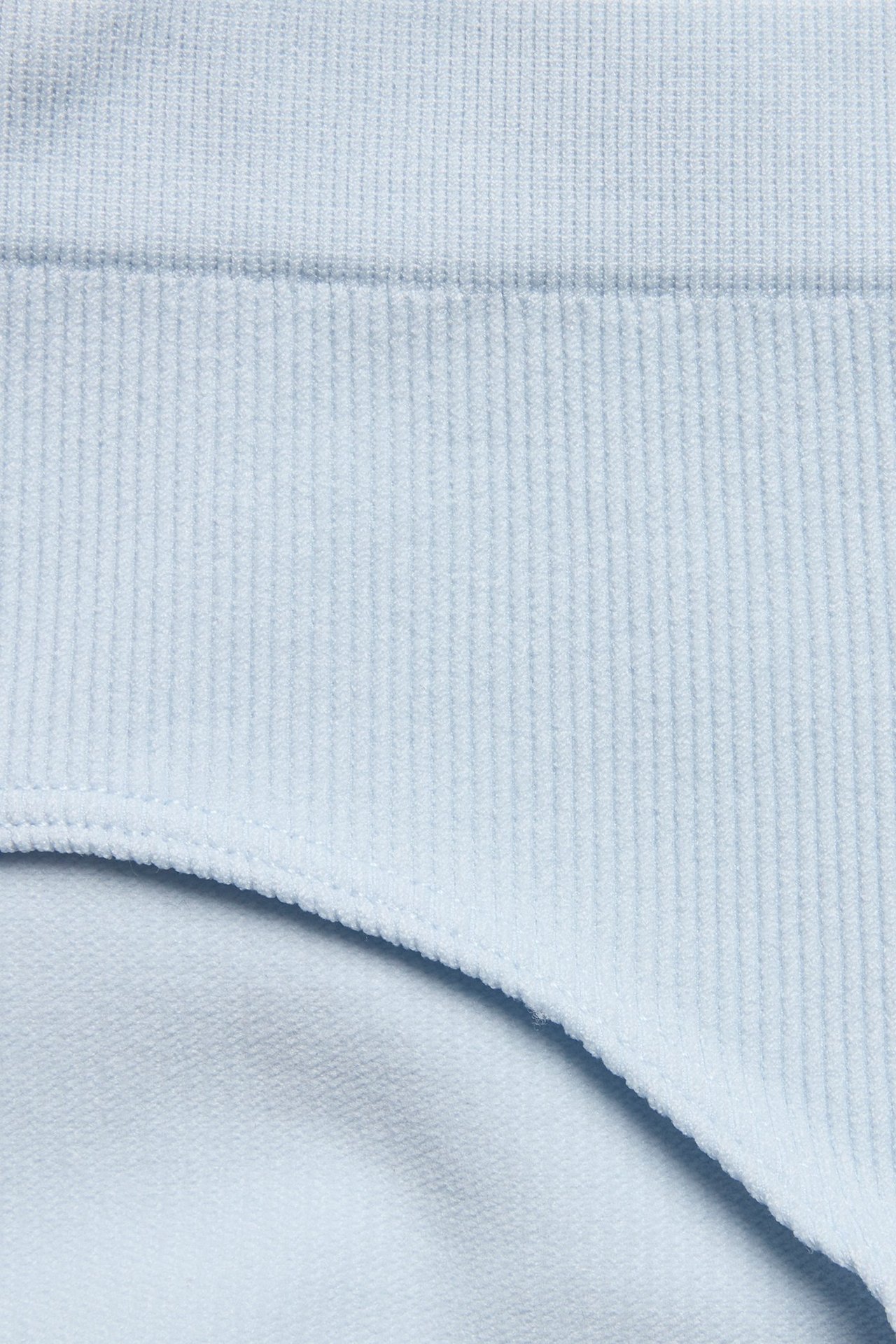 Nærbilde av lyseblå sømløse ribbestrikkede hipster-truser i polyamid og elastan.