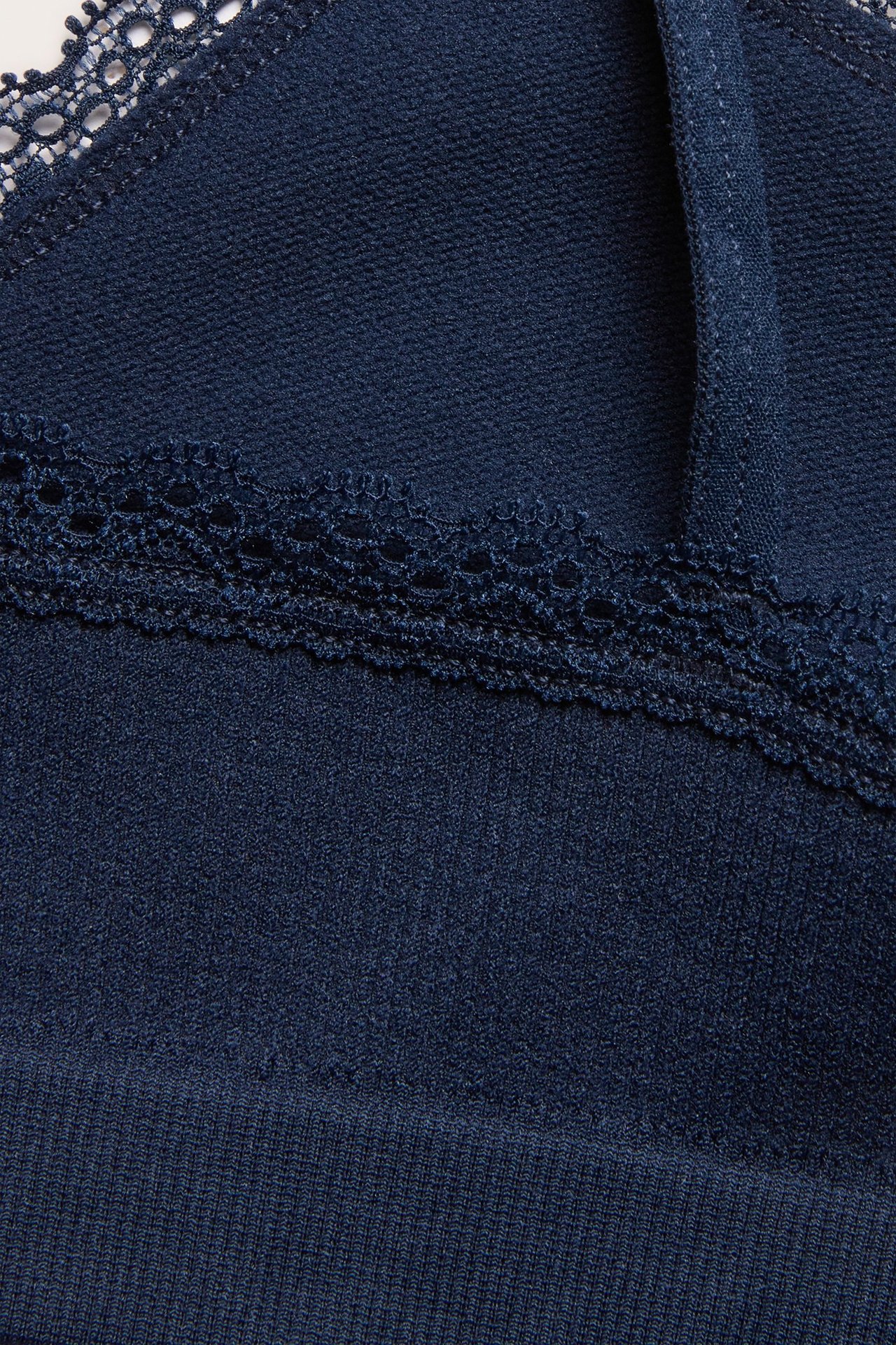 Zbliżenie na ciemnoniebieski bezszwowy prążkowany top z delikatną koronkową krawędzią.