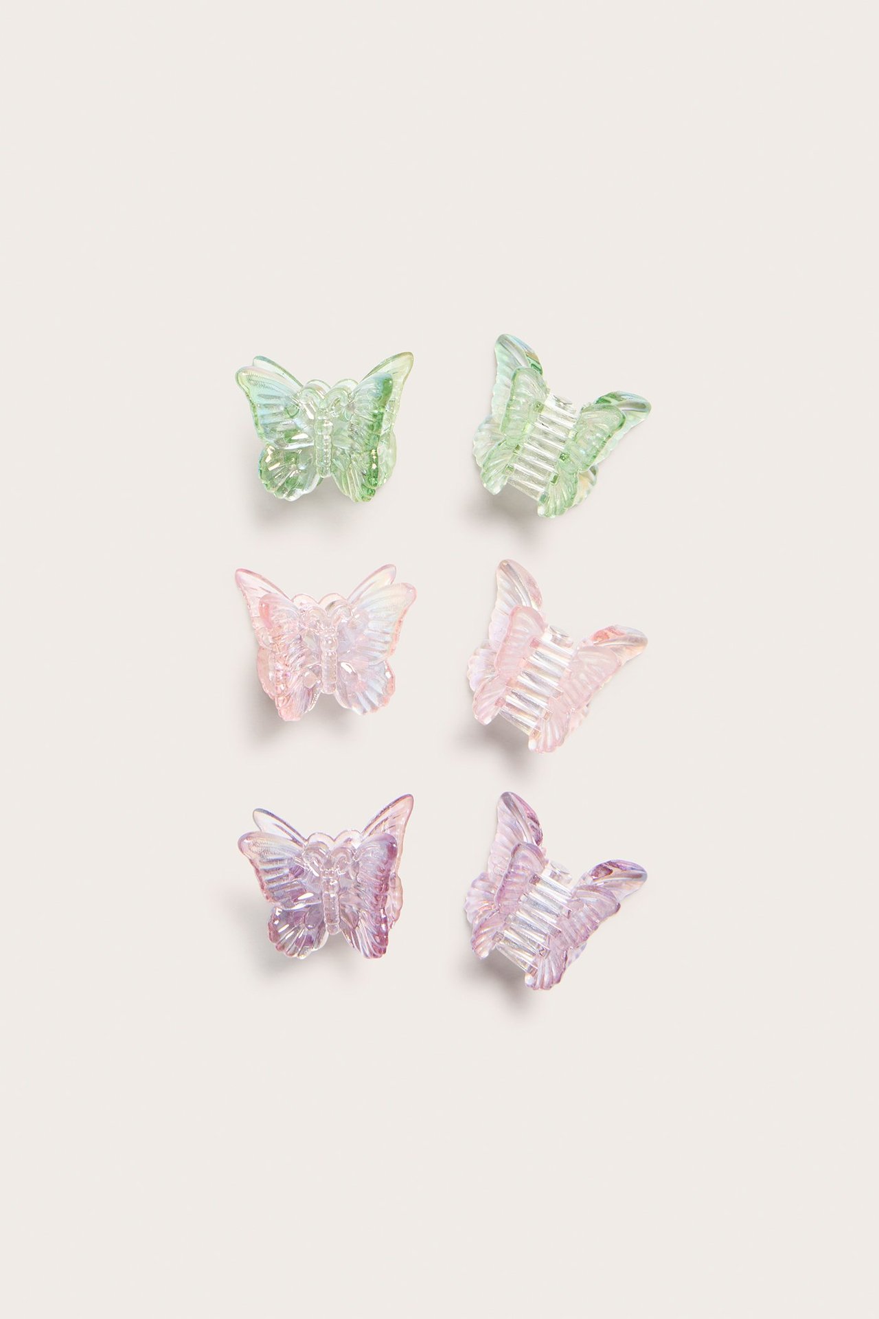 Widok z góry: sześć plastikowych spinek-motyli w jasnej zieleni, różu i liliowym.