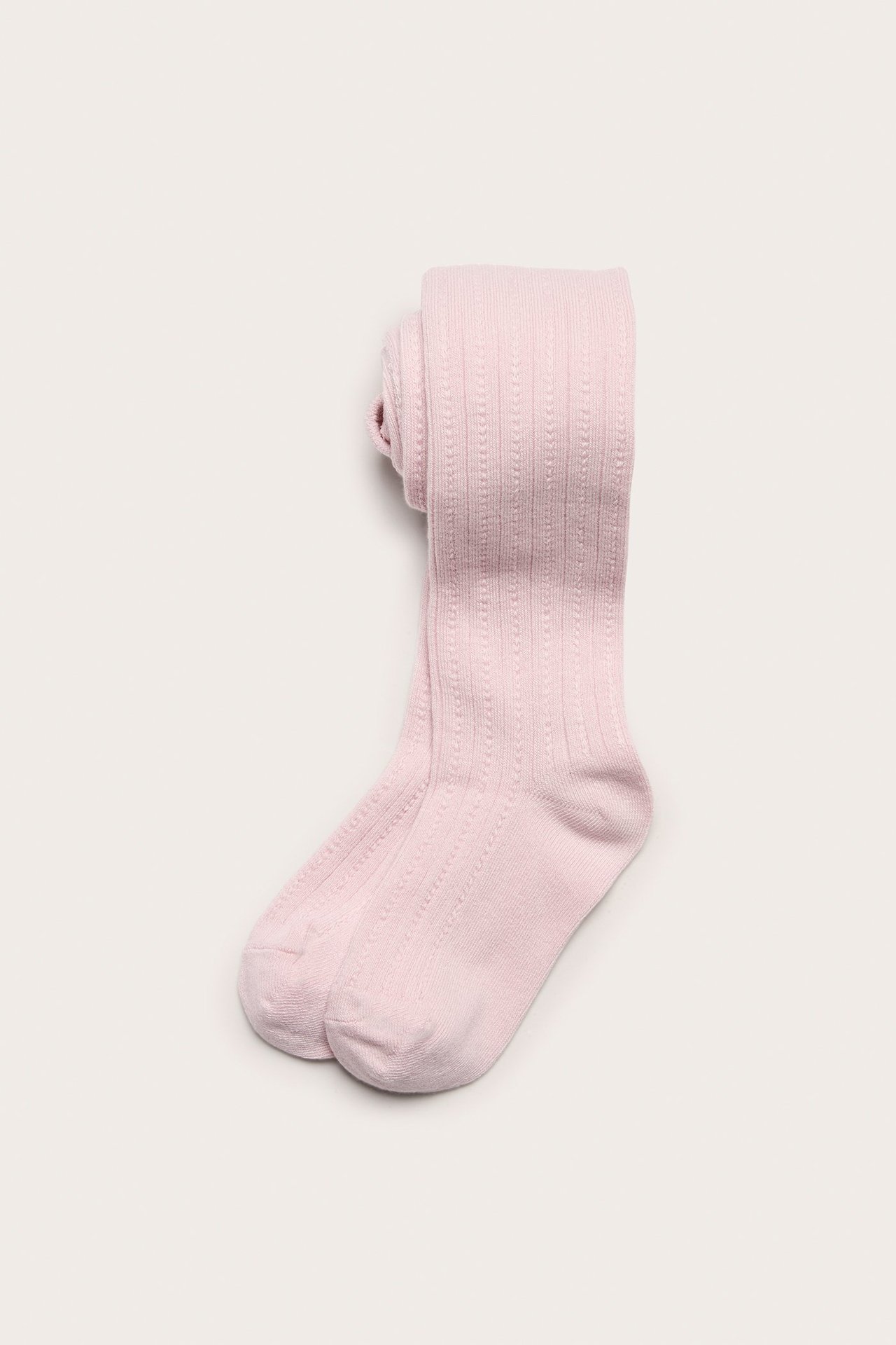 Ylhäältä kuvattu taiteltu vaaleanpunainen lasten sukkahousu, jossa on neulottu kuvio.