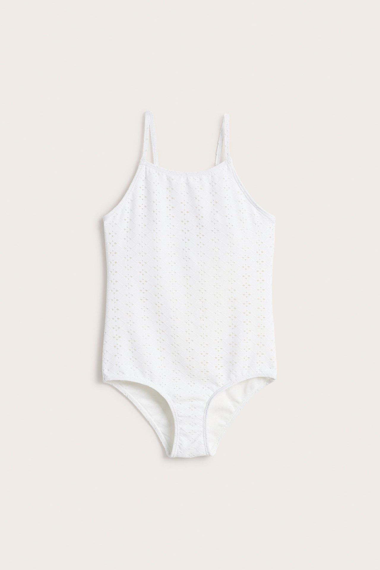 Edestä, luonnonvalkoinen lasten uimapuku broderie anglaise -kuviolla ja ohuilla olkaimilla.