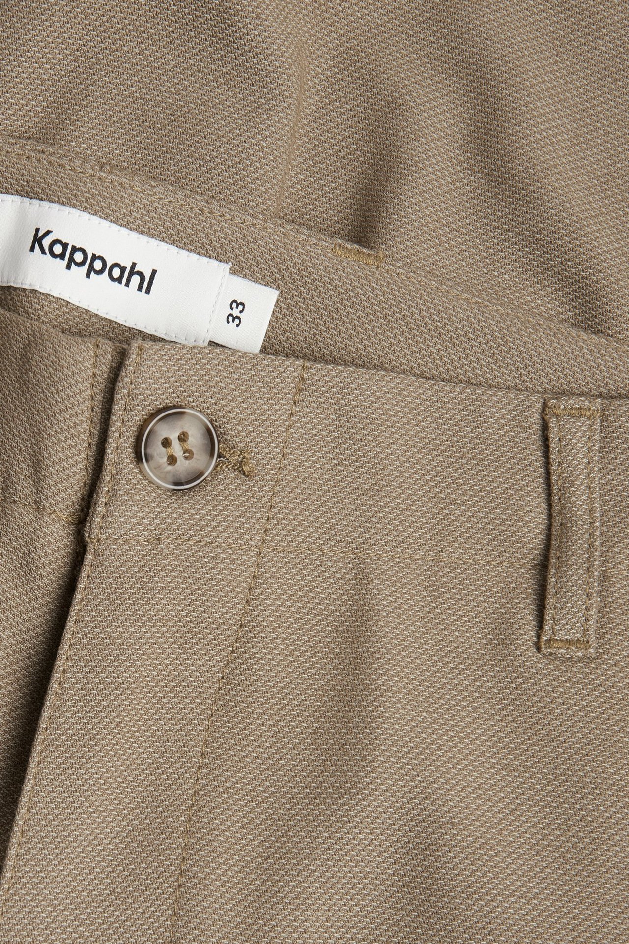 Zbliżenie na brązowe męskie szorty chino ze streczem, ukazujące teksturowany materiał, zapięcie na guzik i szlufkę.