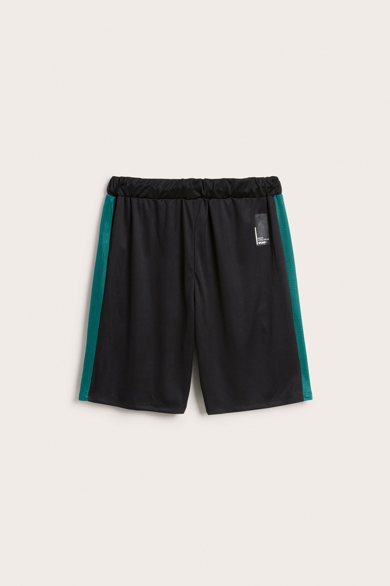 Framifrån svarta träningsshorts i polyester med resårlinning och gröna sidoränder i mesh.