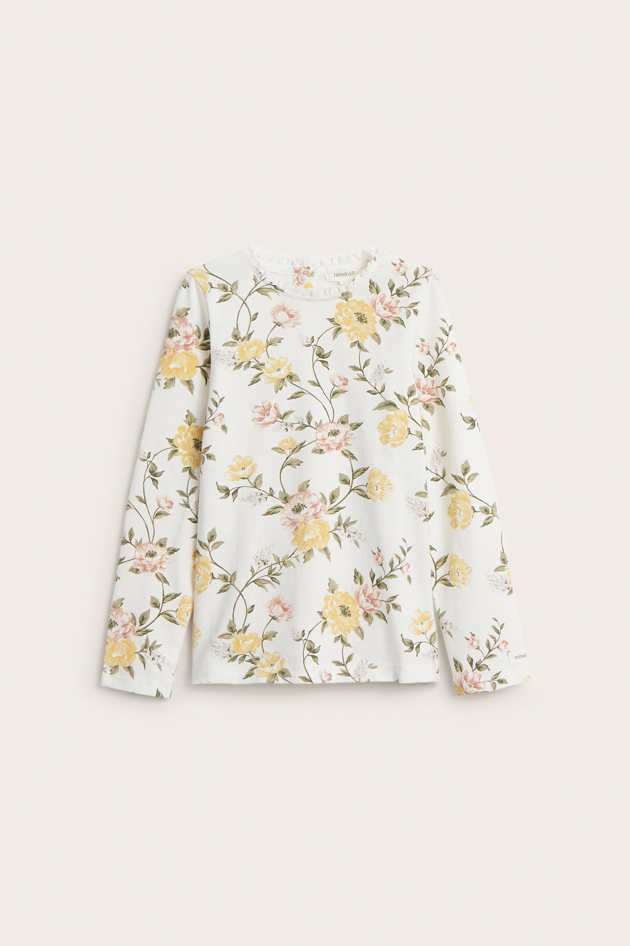 Forfra: Offwhite langermet jerseytop med gult og rosa blomstermønster, liten blondekant i halsen.