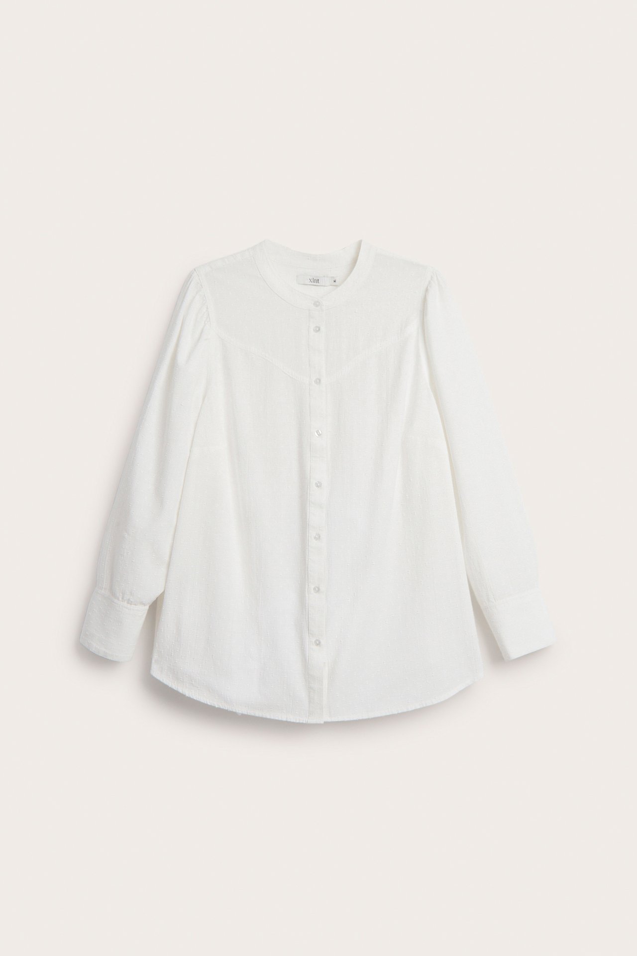 Frontvisning av en offwhite bomullsbluse med rund hals, hel knappestolpe og ballongermer.