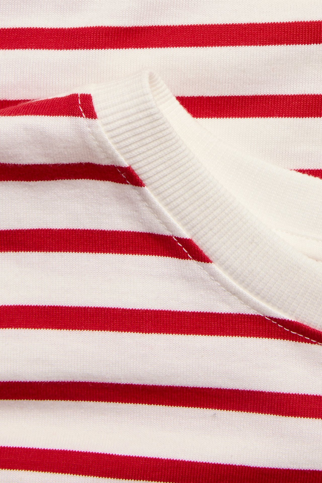 Zbliżenie na czerwono-białą bluzkę w paski z bawełnianego dżerseju z prążkowanym dekoltem.